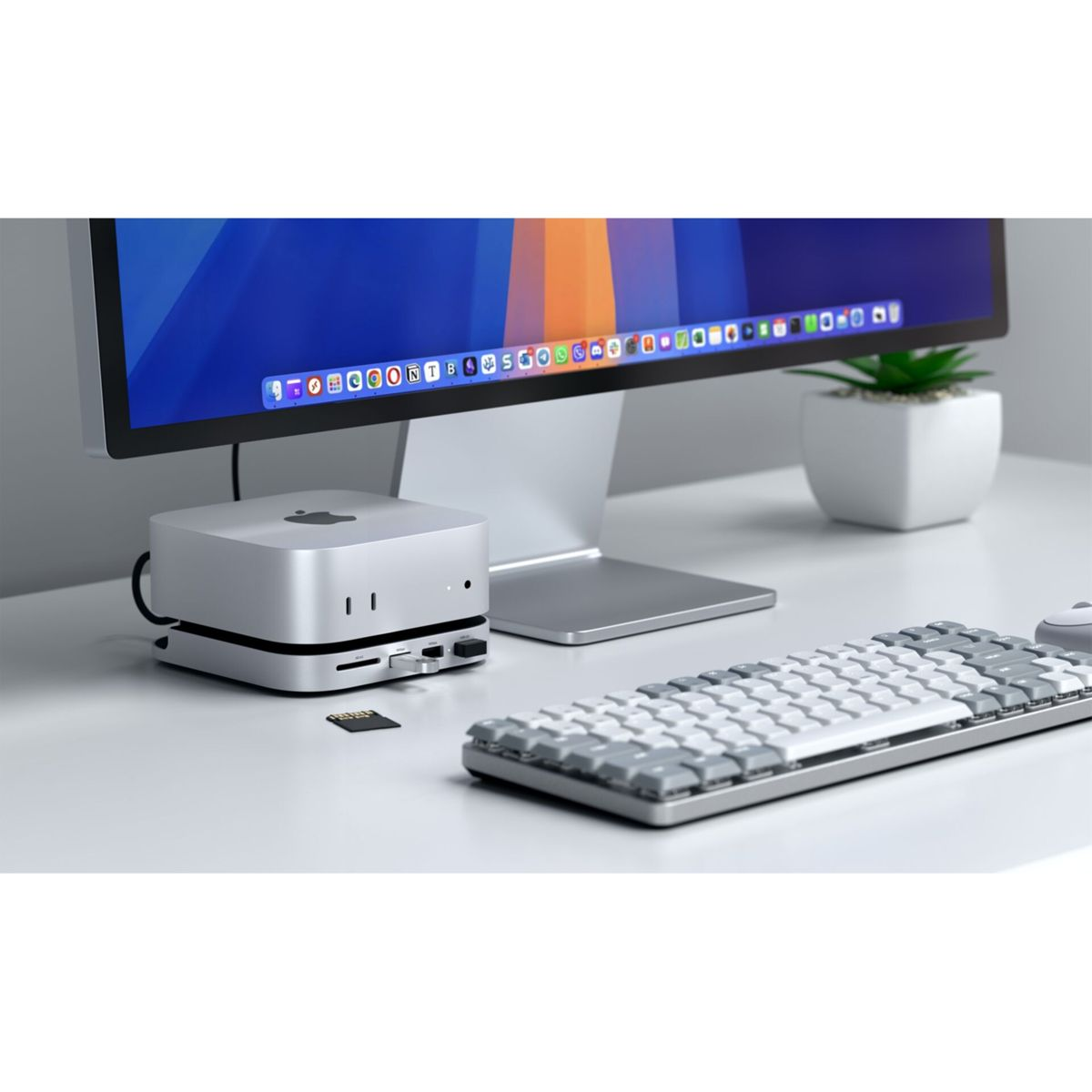 Ein silberner Apple Mac Studio steht auf einem Schreibtisch mit Monitor, Tastatur und Maus.