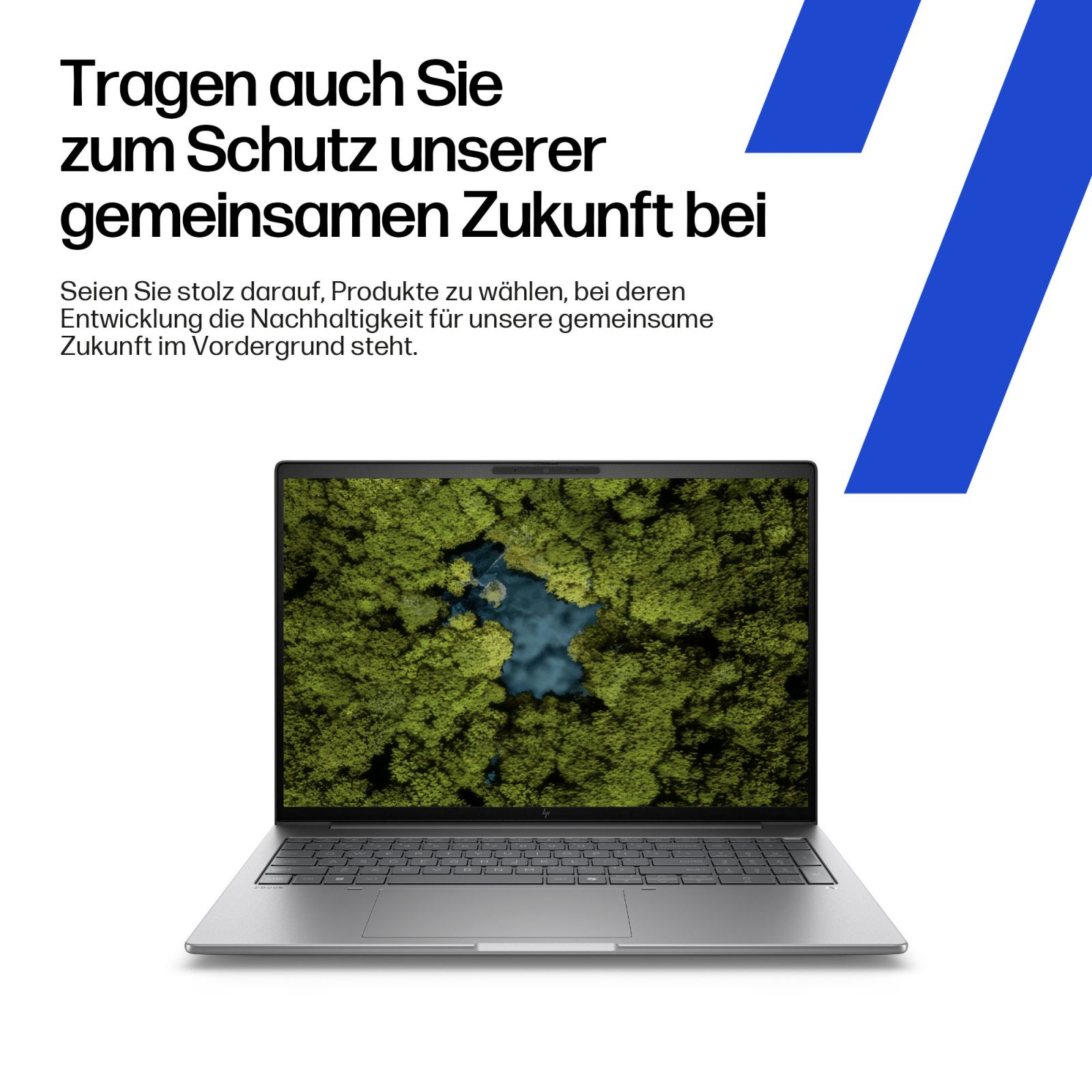 Srebrny laptop wyświetla widok z lotu ptaka na zielony las i niebieską wodę. Tekst powyżej.