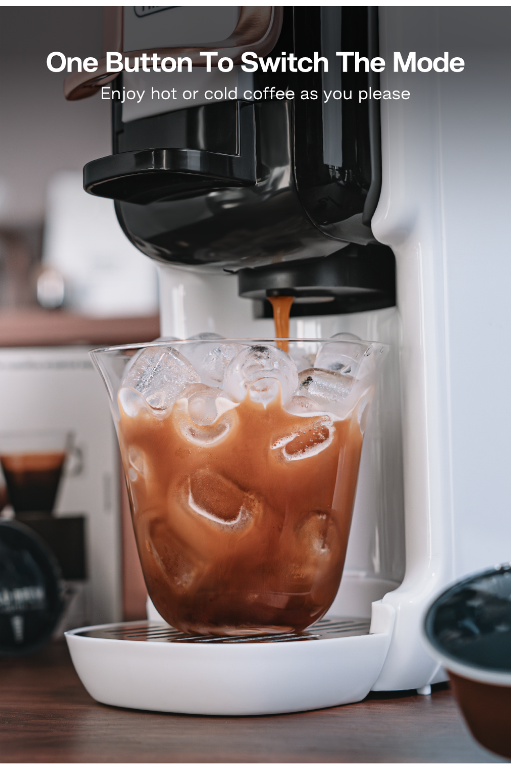Cafetera dispensando café helado en un vaso lleno de cubitos de hielo.