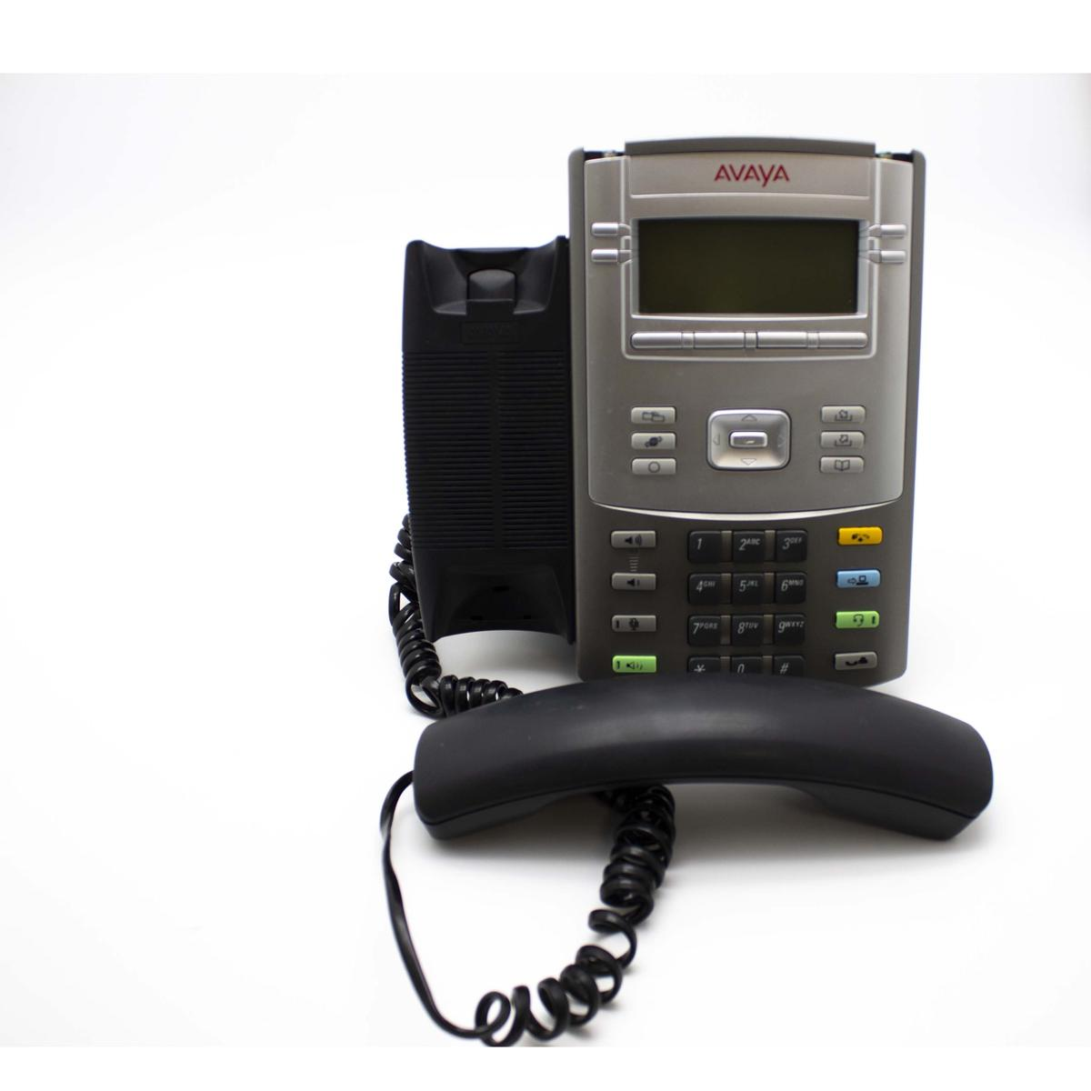Un telefono da ufficio Avaya argentato con cornetta nera e cavo a spirale, su sfondo bianco.