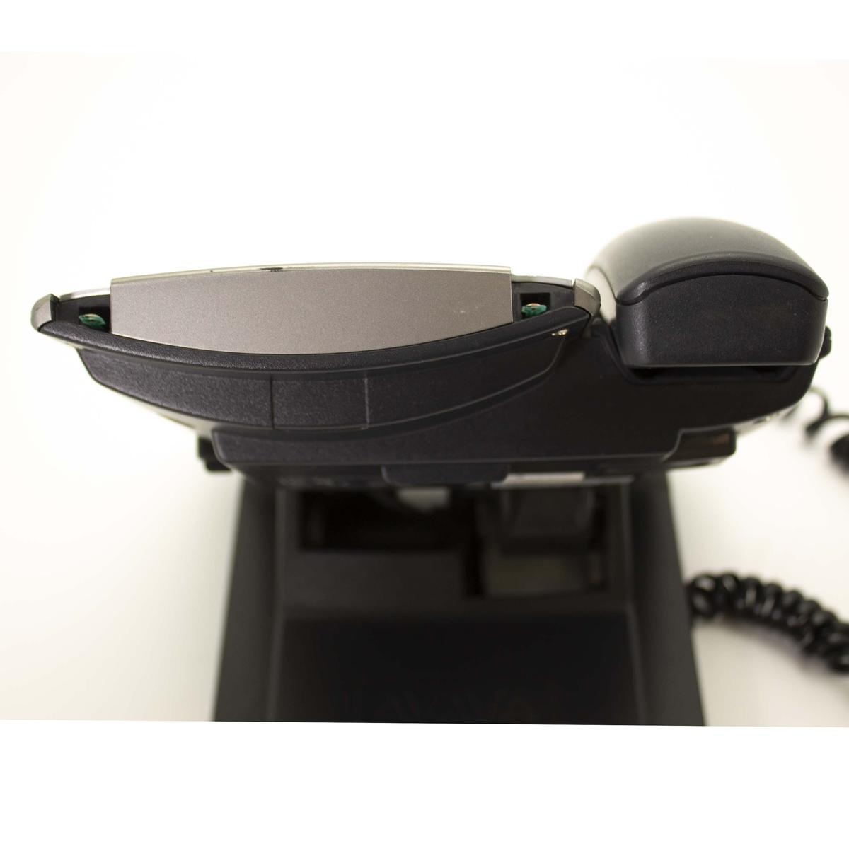 Un telefono da ufficio nero con accento argentato poggia sulla sua base nera su sfondo bianco.