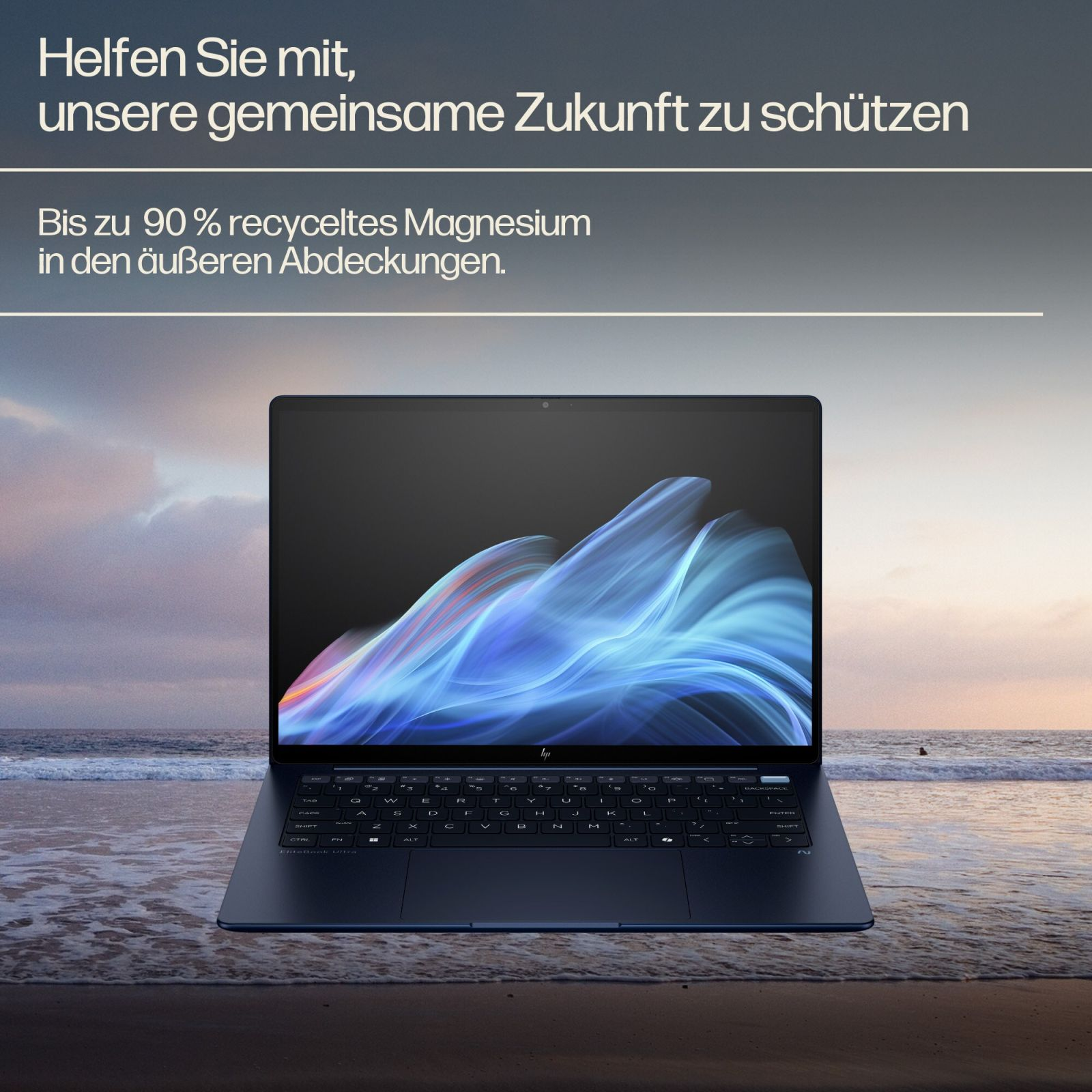 Ein dunkelblauer Laptop steht am Strand, mit Wellen und einem Sonnenuntergang im Hintergrund.