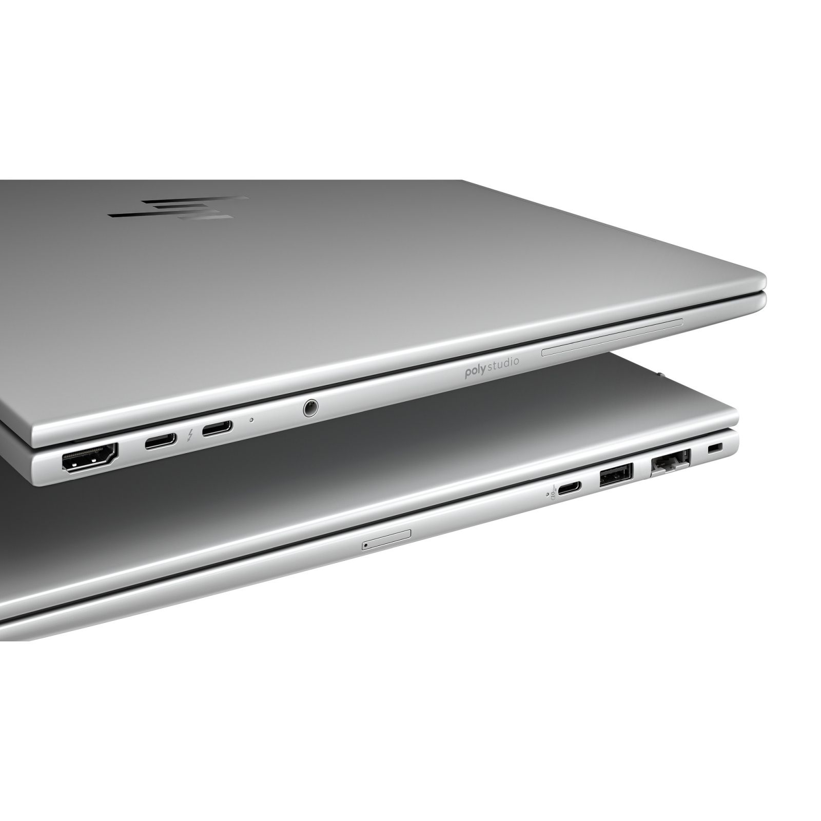 Dwa srebrne laptopy ułożone jeden na drugim, pokazujące porty i napis 'poly studio'.