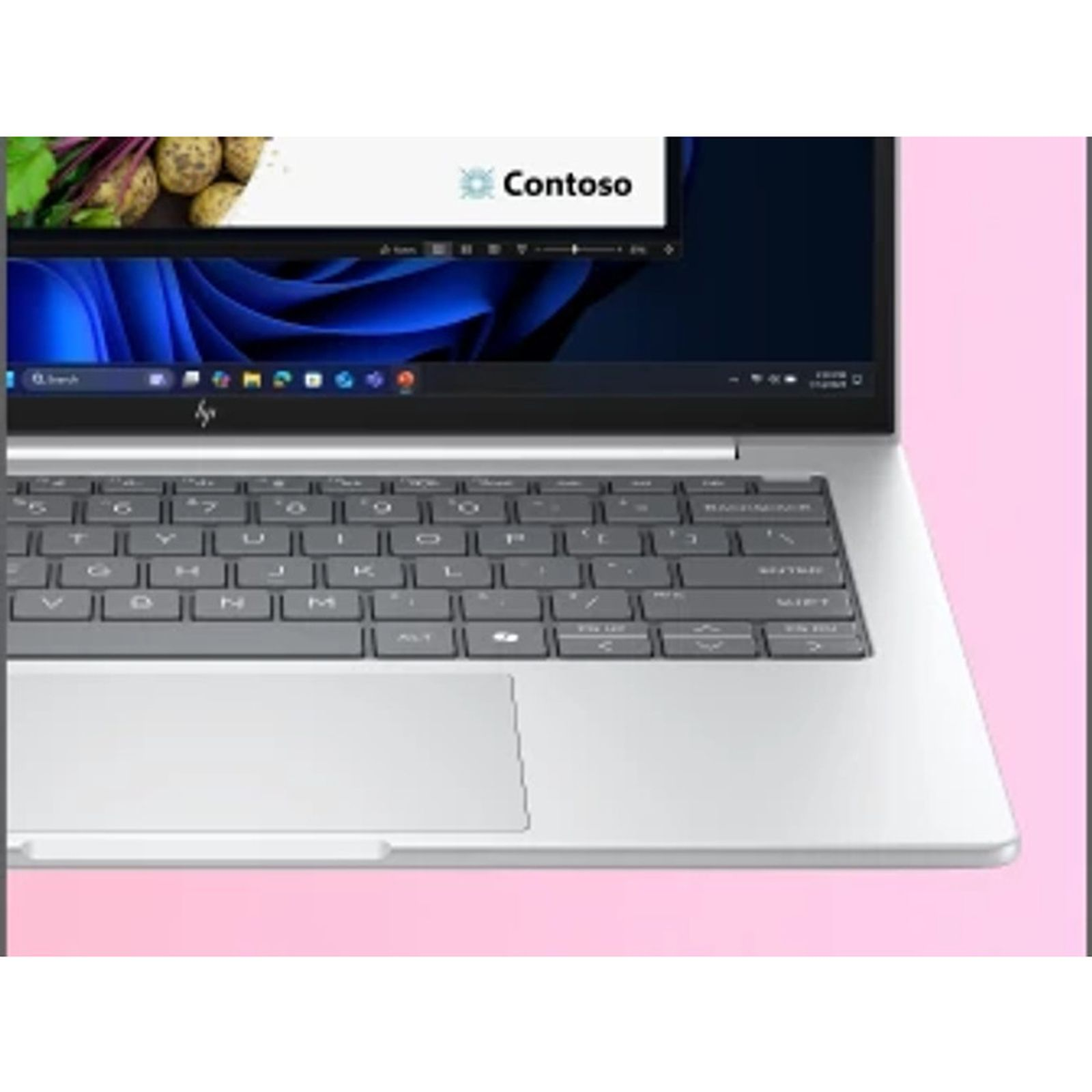 Srebrny laptop wyświetla ekran z logo Contoso, niebieską sztuką abstrakcyjną i klawiaturą.