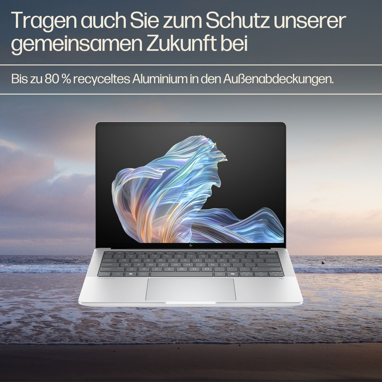 Srebrny laptop stoi na plaży z rozbijającymi się falami. Ekran wyświetla abstrakcyjną sztukę.