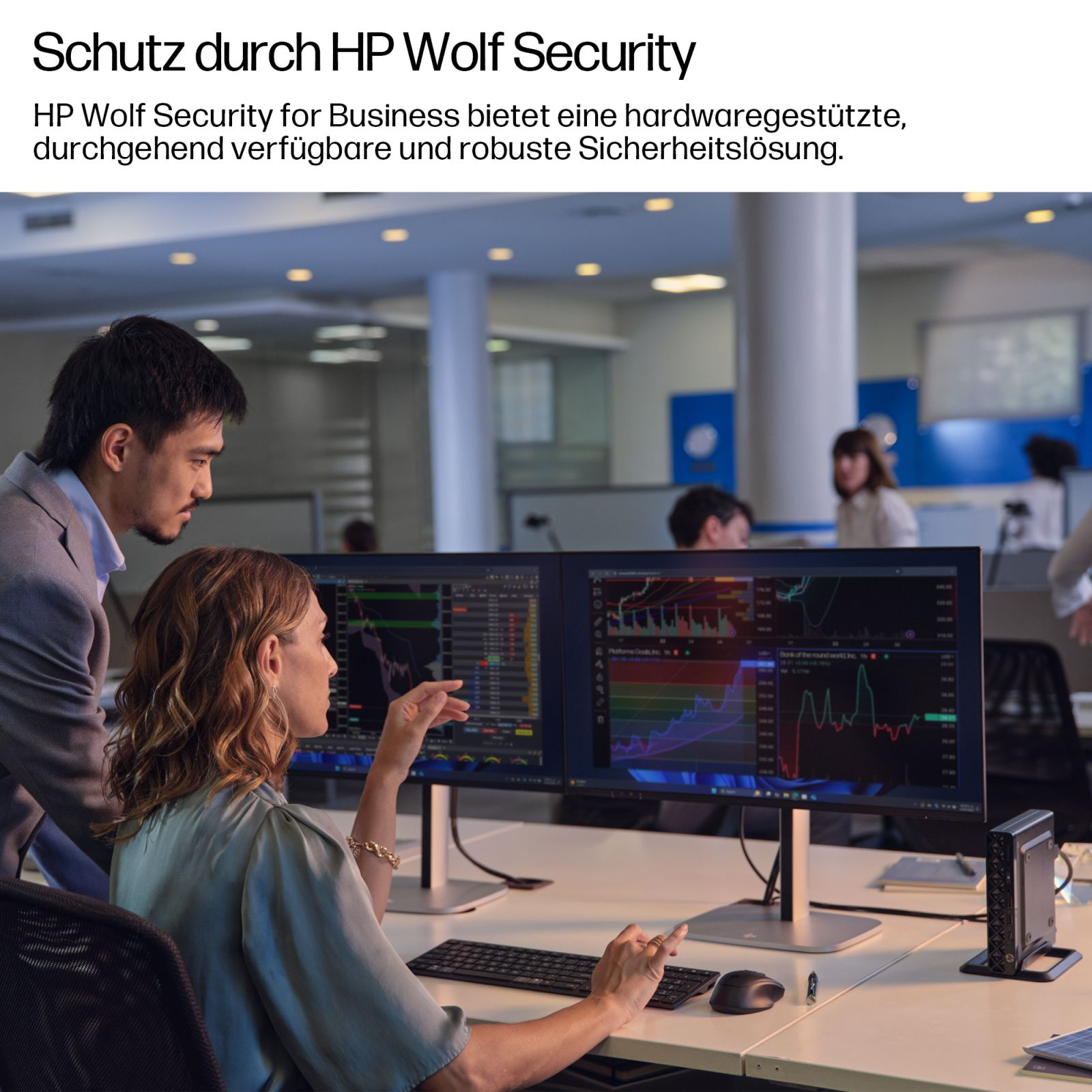 Mitarbeiter blicken auf zwei Bildschirme mit Finanzdiagrammen im Büro.