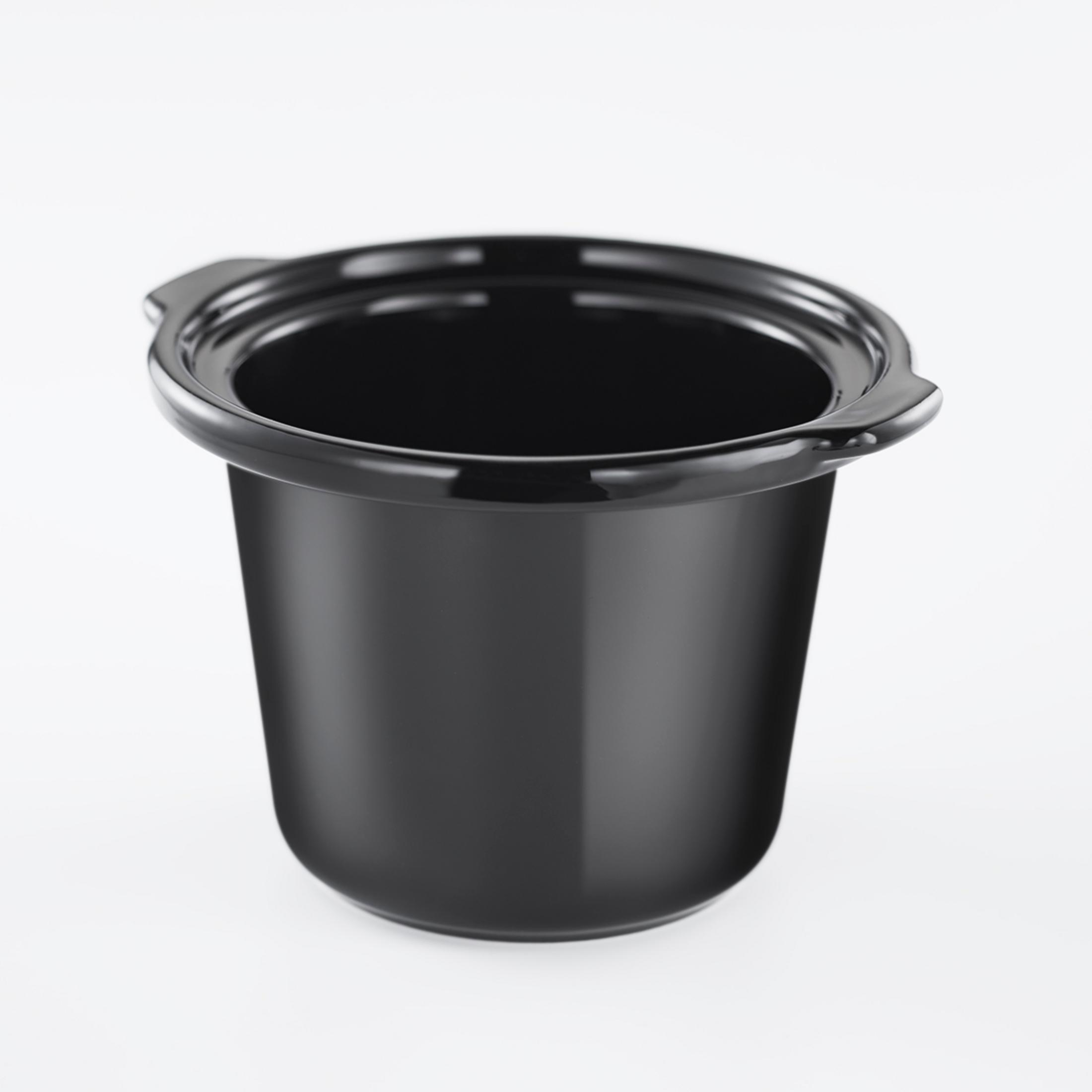 Un inserto nero per slow cooker su sfondo bianco. È vuoto e pulito.