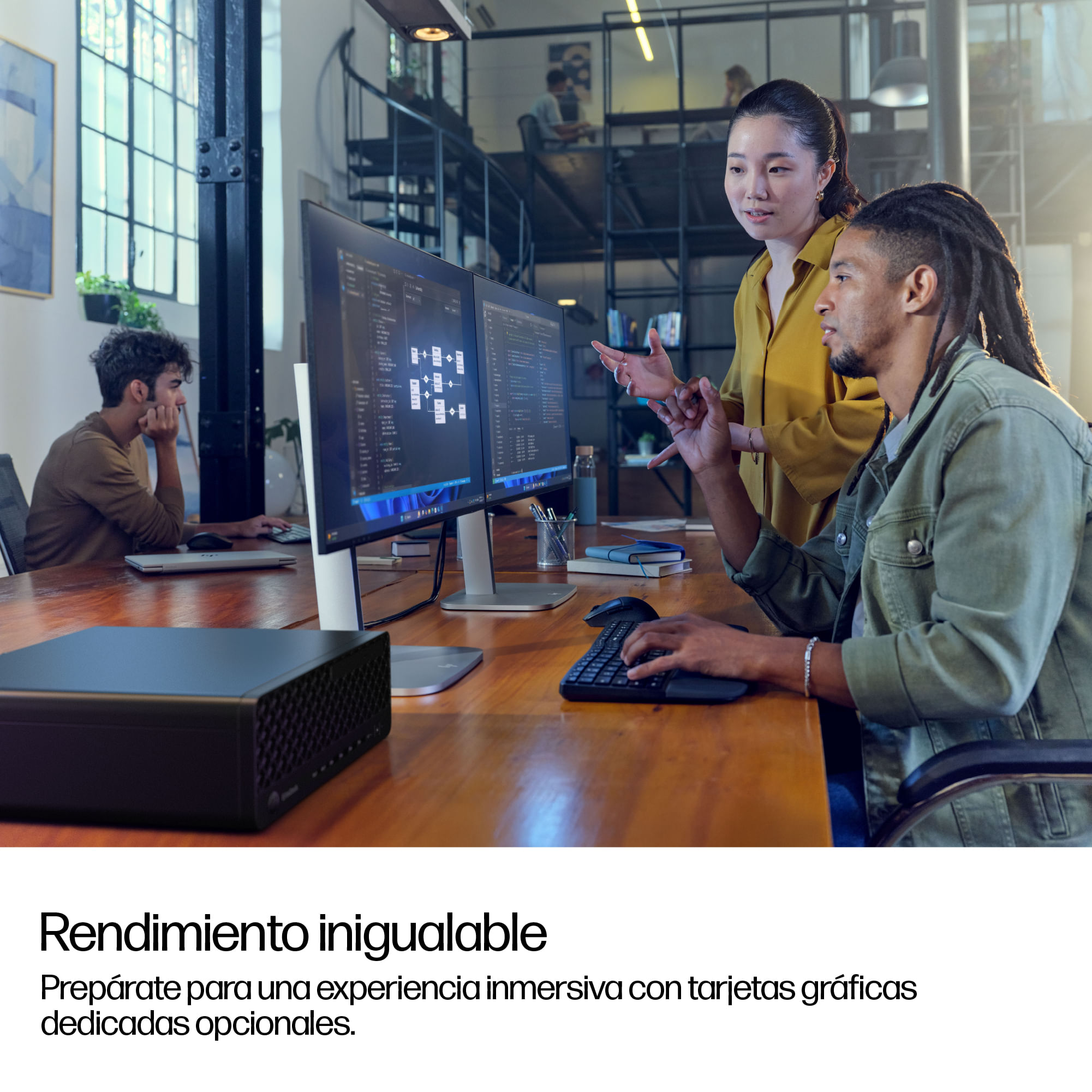 Personas trabajan en computadoras en una oficina moderna con grandes ventanales.