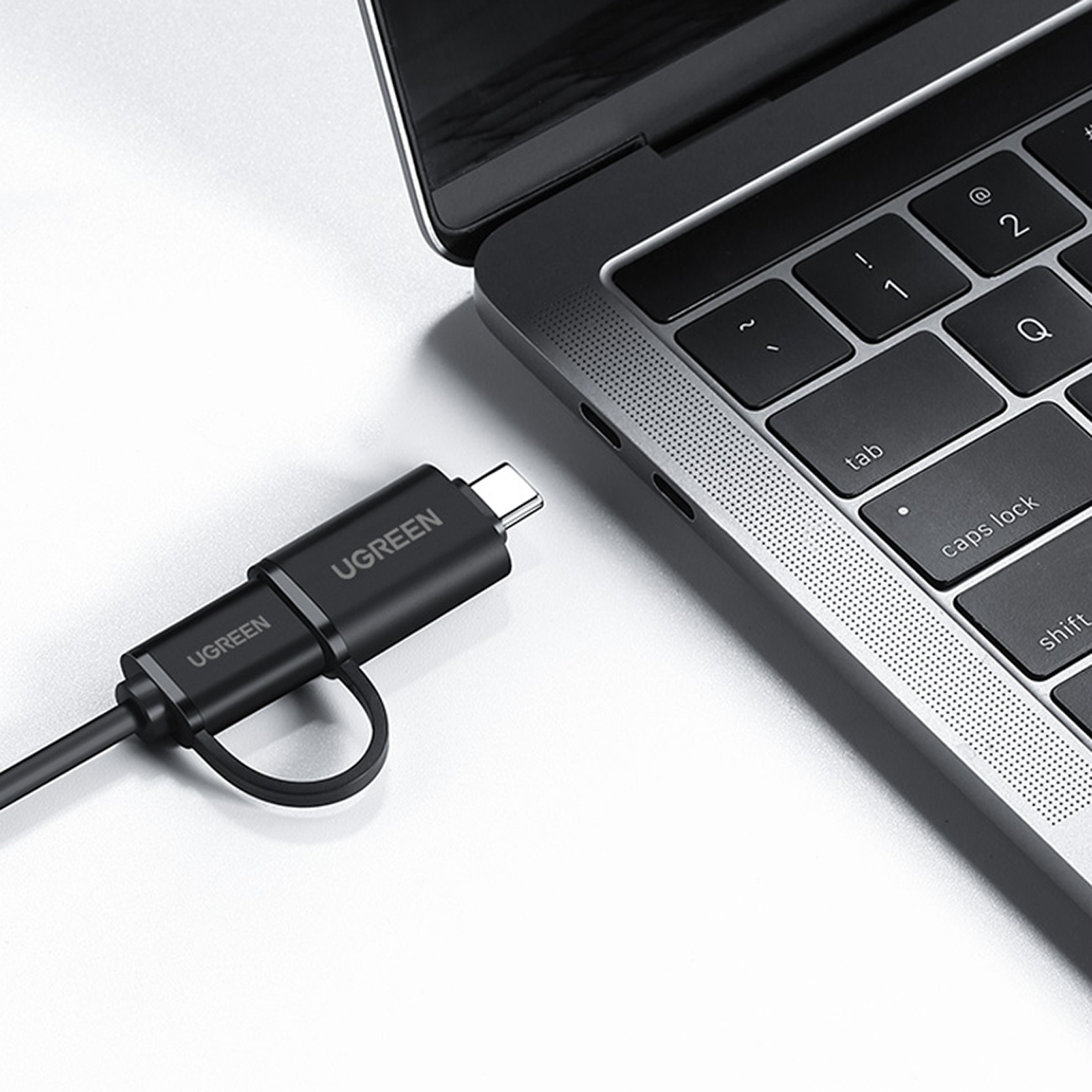 Czarny kabel UGREEN USB-C podłączony do srebrnego laptopa.
