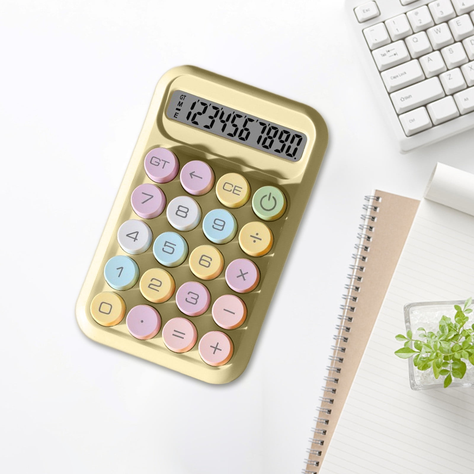 Ein gelber Taschenrechner mit bunten Tasten liegt neben einer Tastatur und einem Notizbuch.
