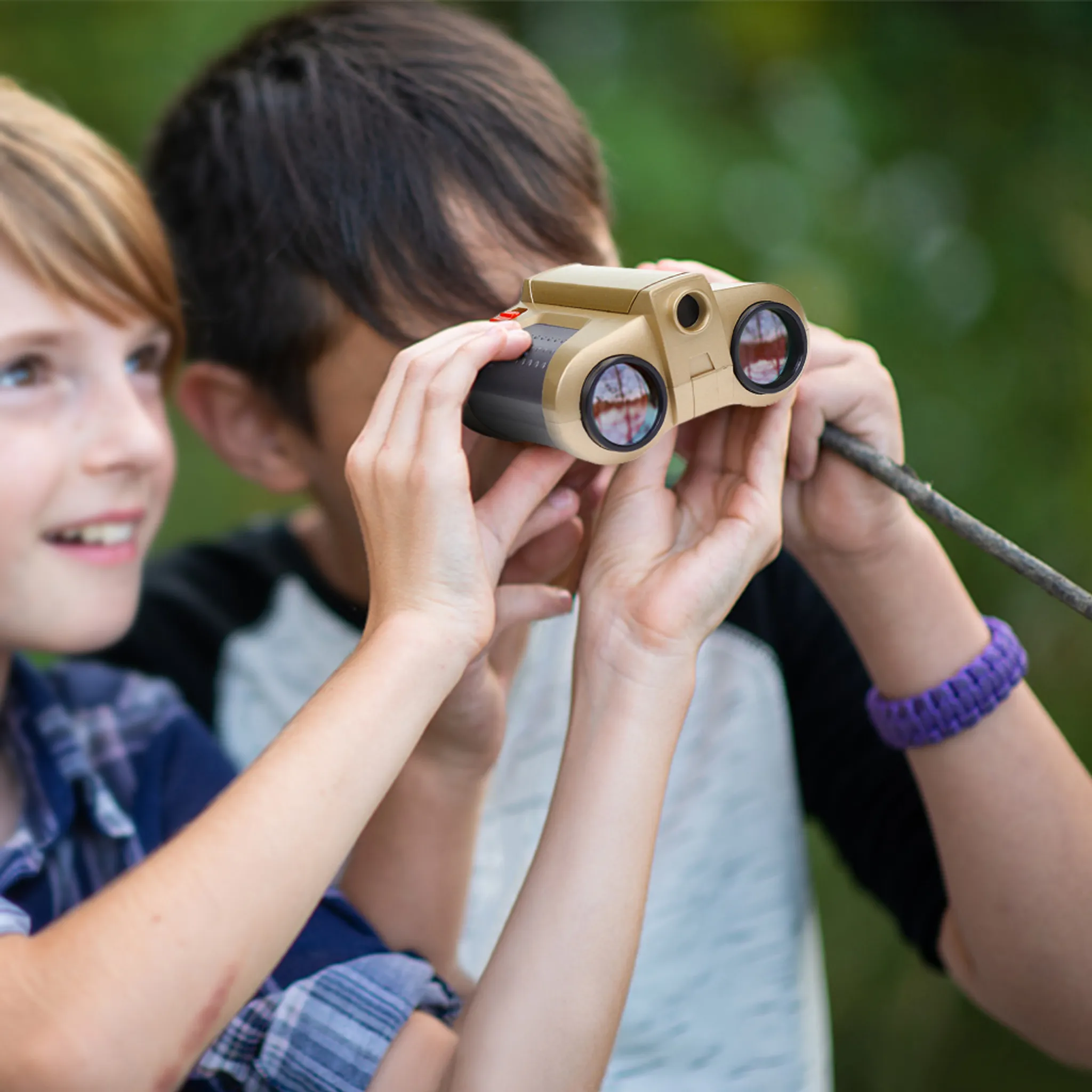 Zwei Kinder untersuchen mit einem Fernglas die Natur. Ein Junge hält es.