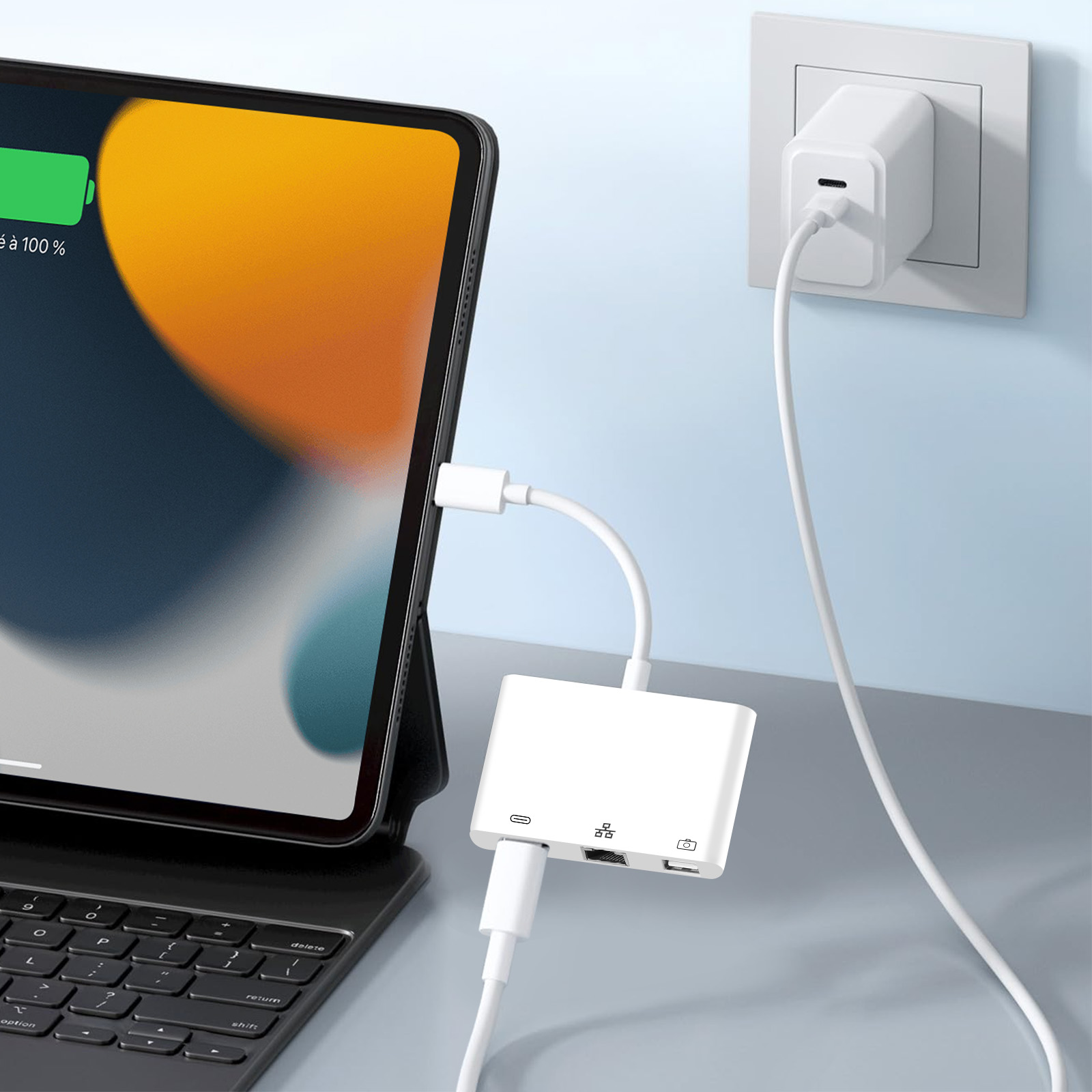 Tablette en charge via hub connecté à un adaptateur mural et clavier.