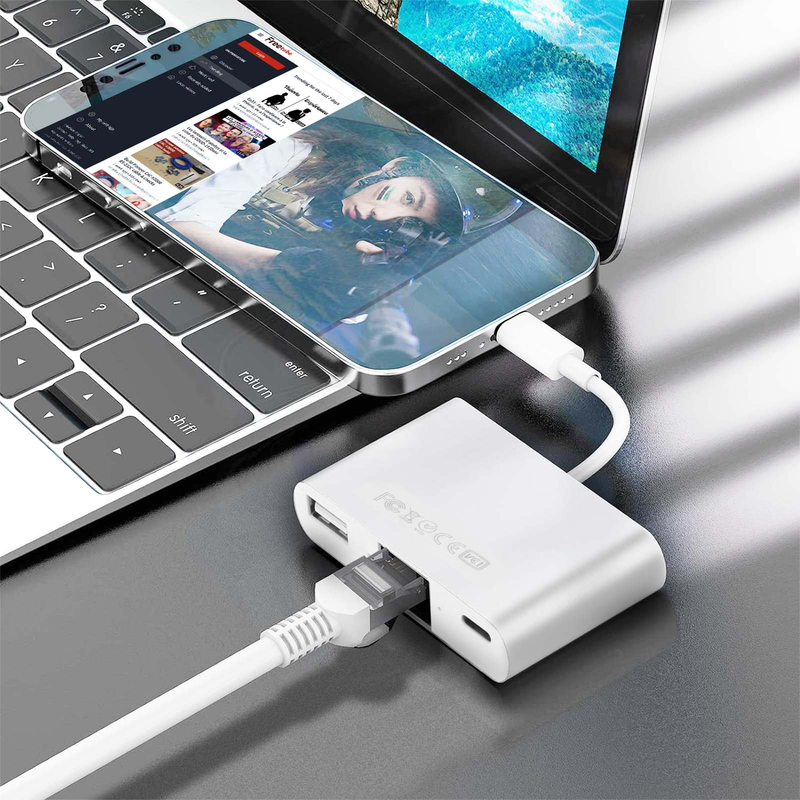 Un hub USB-C blanc connecte un téléphone et un câble Ethernet à un ordinateur portable.