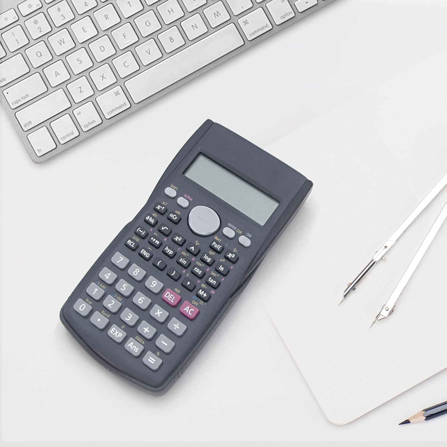Ein wissenschaftlicher Taschenrechner, eine Tastatur und ein Zirkel liegen auf einem weißen Schreibtisch.