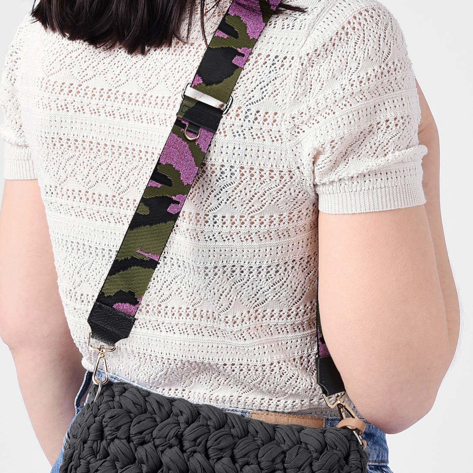 Donna con top uncinetto bianco e jeans blu indossa borsa nera con tracolla mimetica rosa.