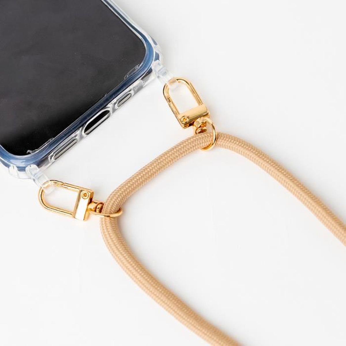 Un telefono in una custodia trasparente con un cordino beige e clip dorate.