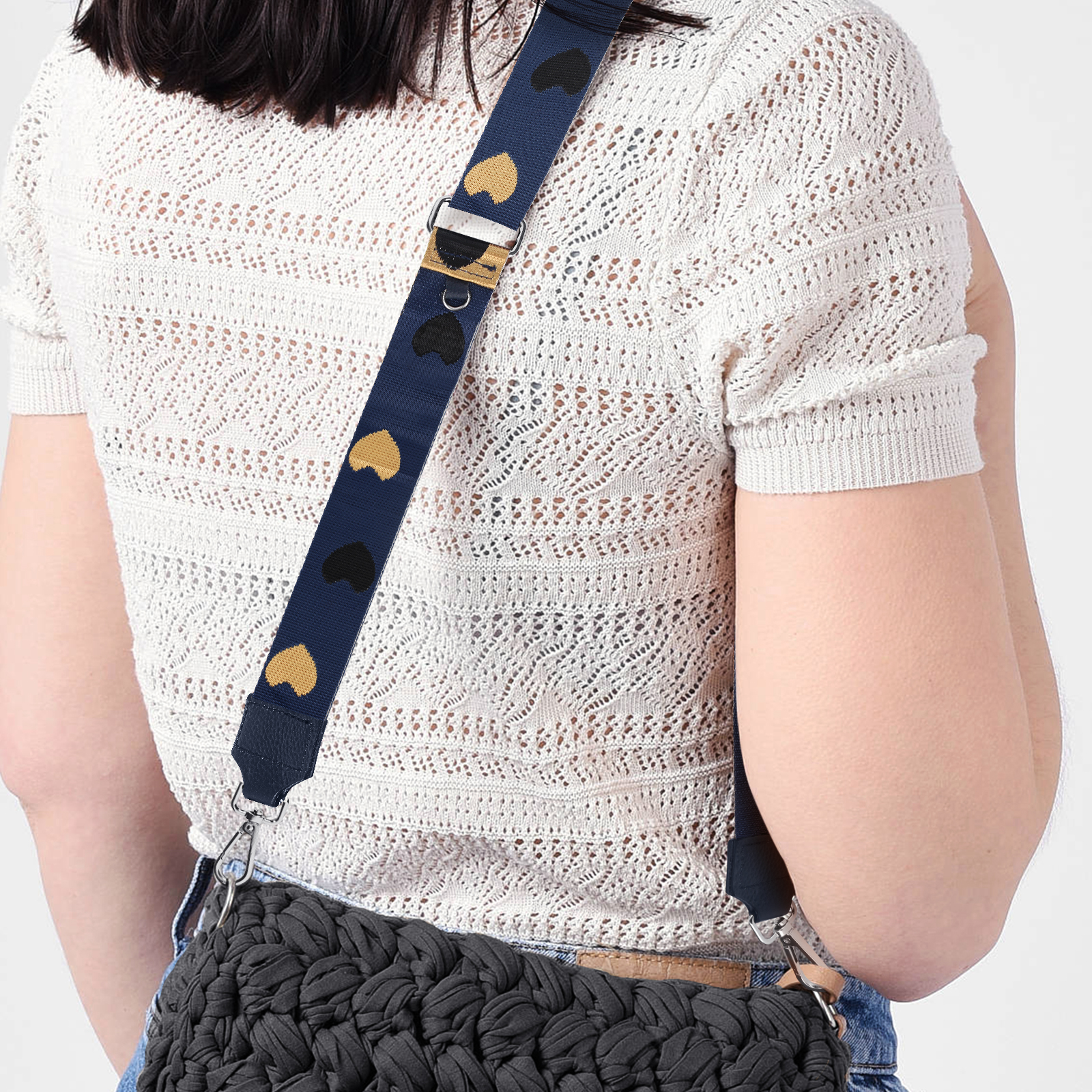 Una donna con capelli scuri indossa un top bianco lavorato a maglia e una borsa uncinetto nera.