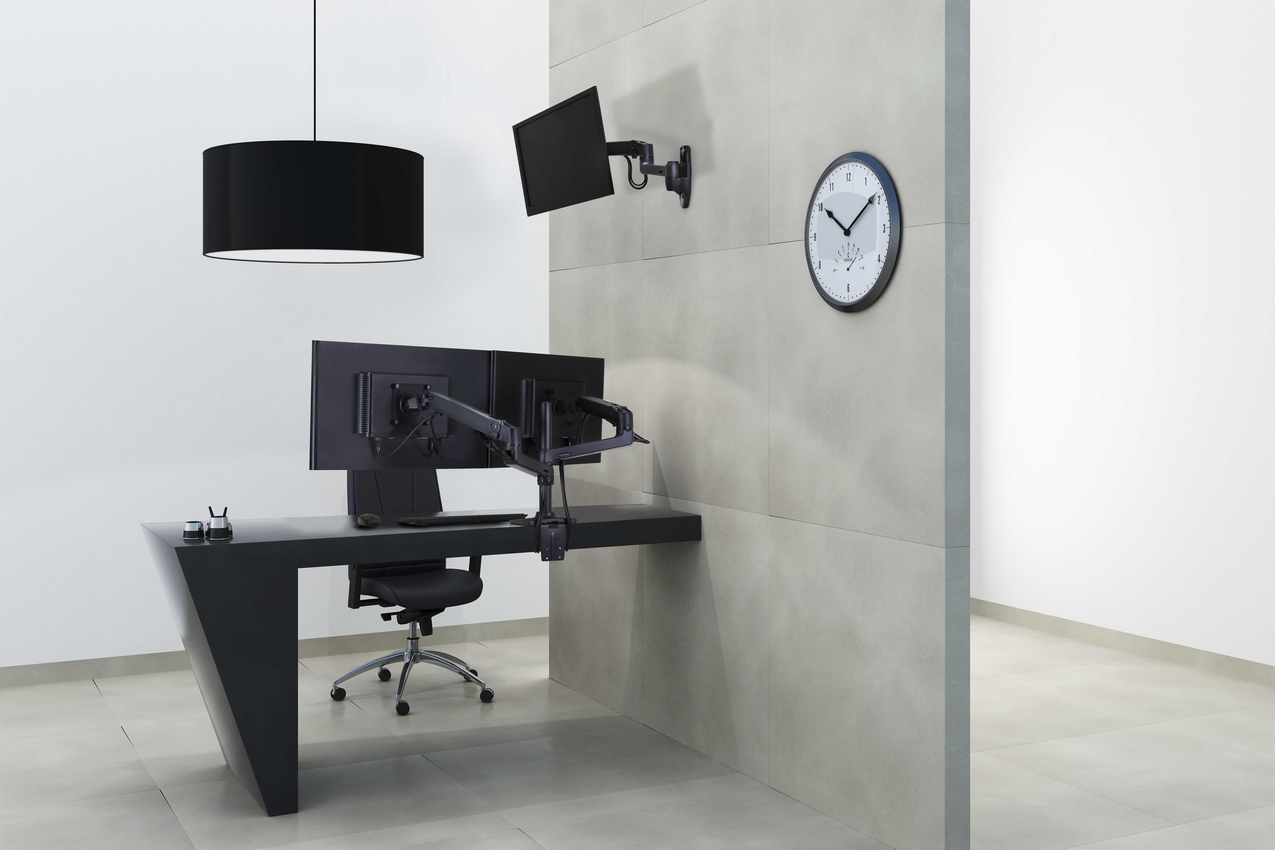 Una moderna scrivania nera con doppio monitor, sedia e orologio da parete.