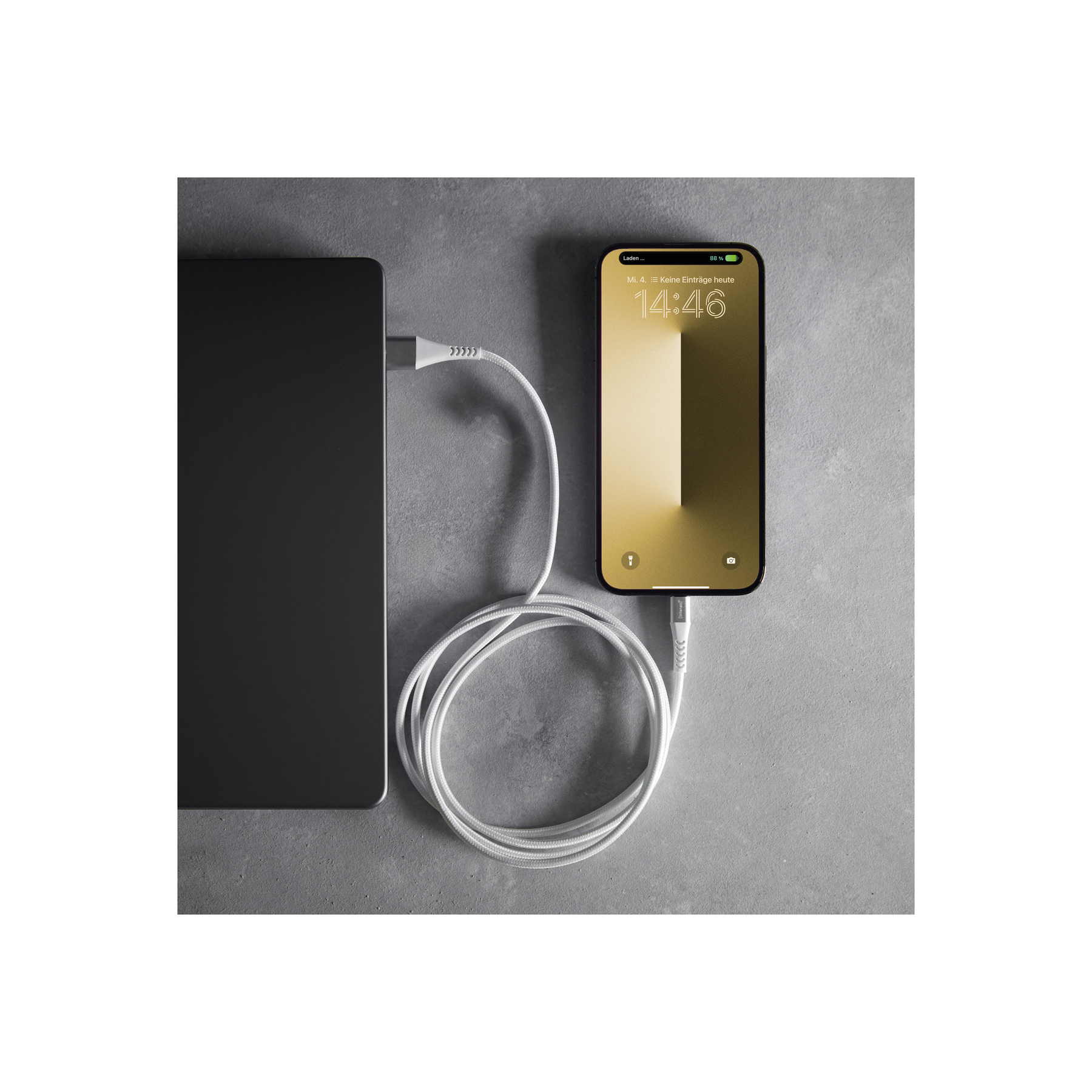 Un câble de chargement gris relie une tablette noire et un smartphone à fond doré.