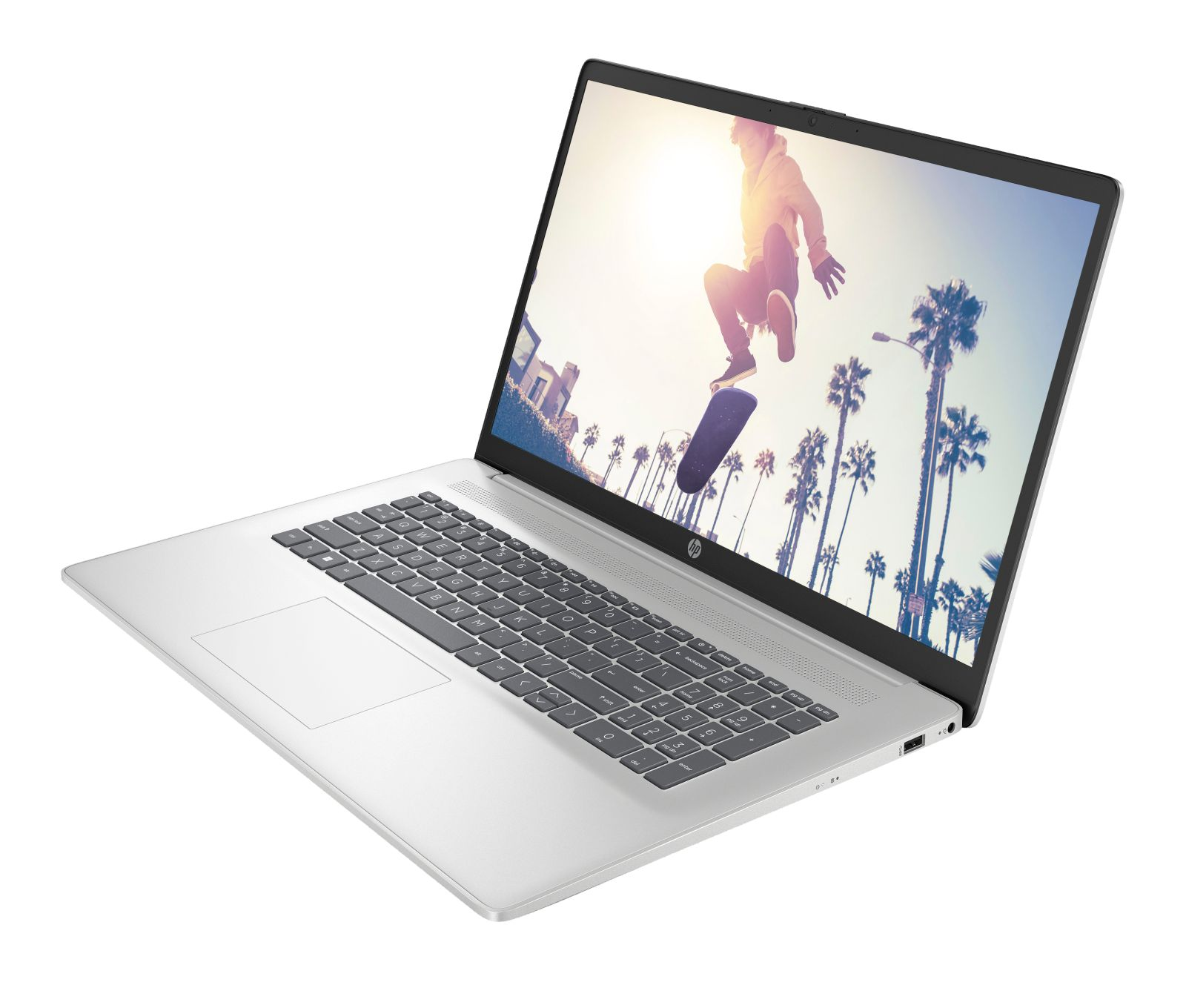 Laptop argento con schermo che mostra uno skater che salta tra le palme.