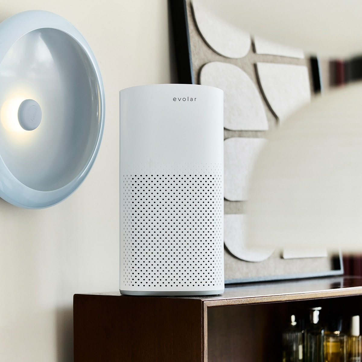 A white cylindrical Evolar air purifier sits on a wooden shelf next to a blue wall light.