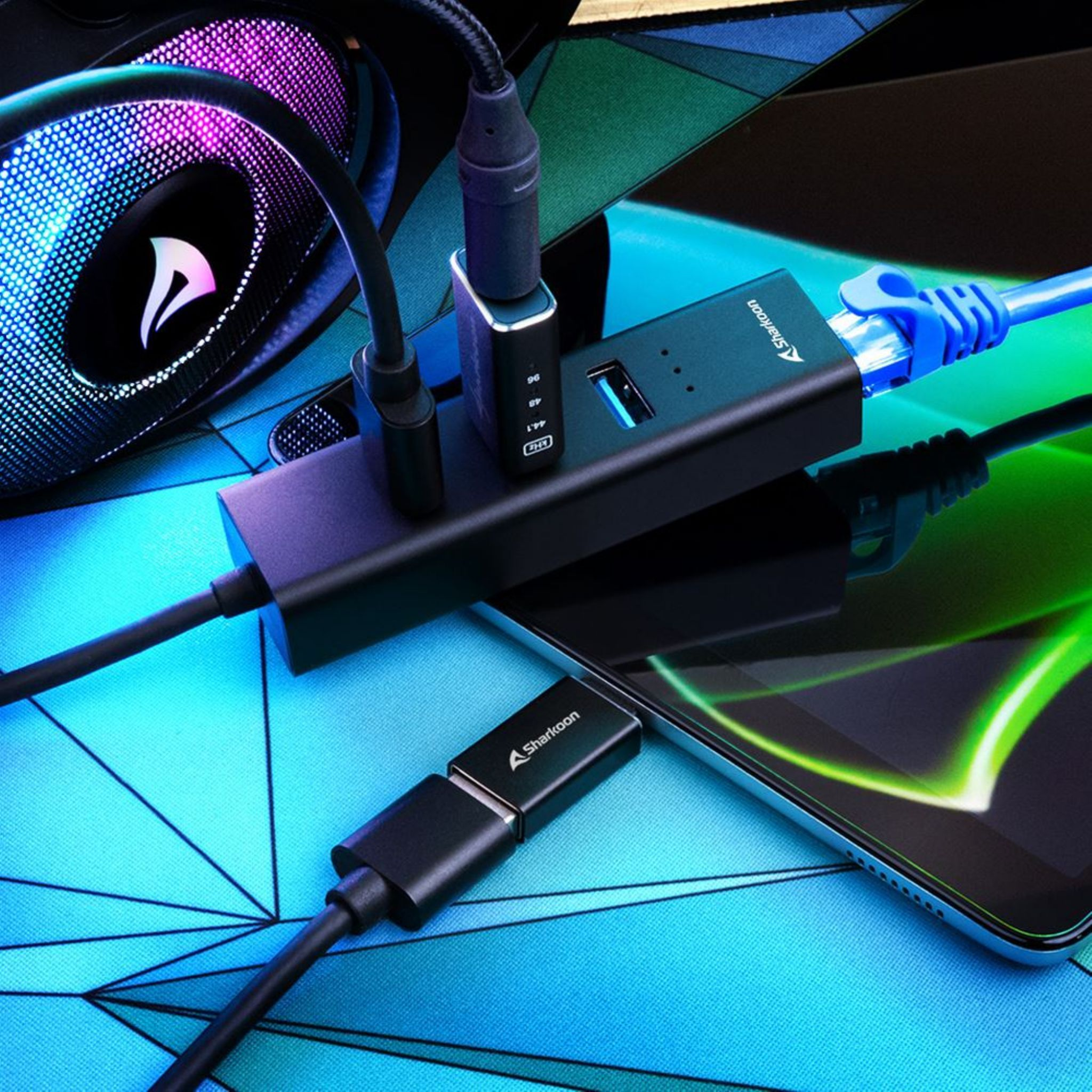 Cuffie gaming con luci RGB, hub USB e telefono collegato via cavo.