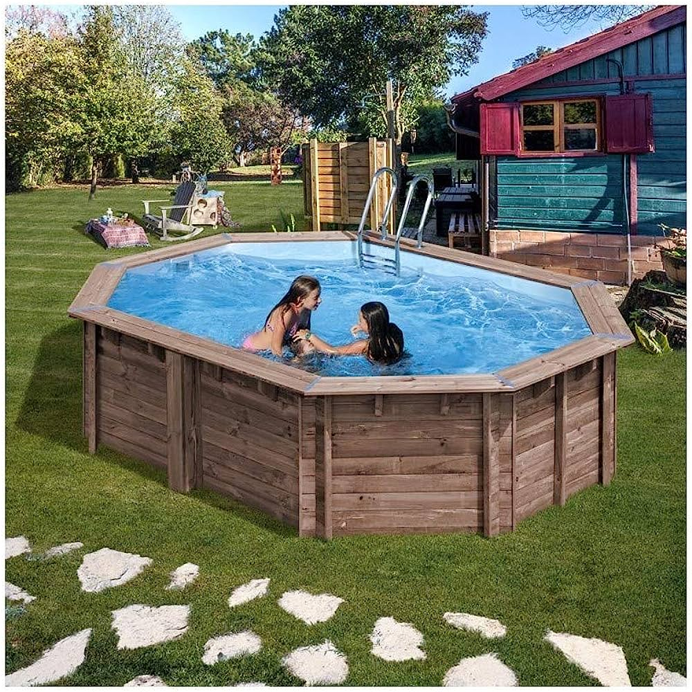 Dos niñas juegan en una piscina octogonal de madera. Una escalera está en el agua. Césped y árboles rodean la piscina.