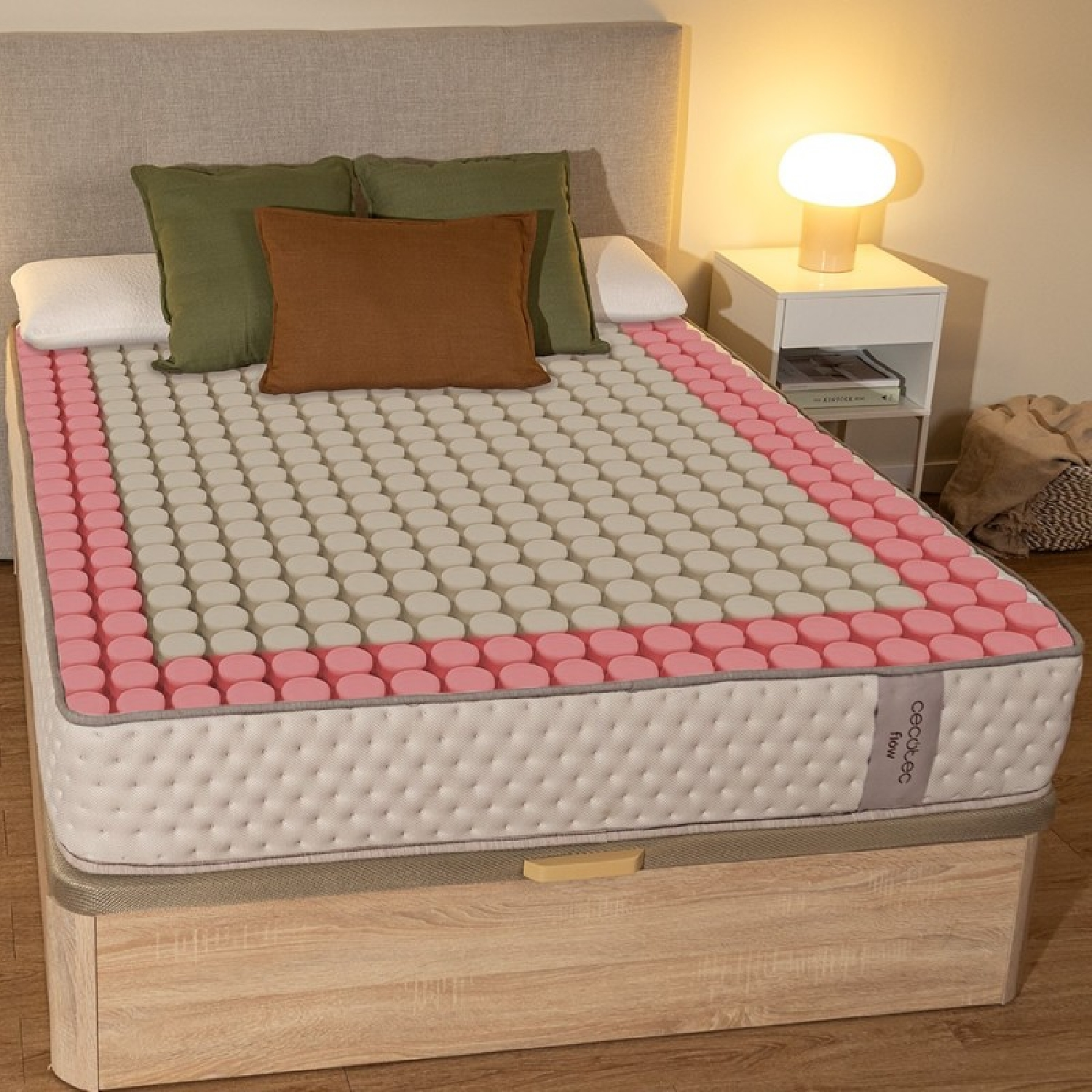 Un materasso con zone circolari rosa e bianche su una base letto in legno con cuscini.