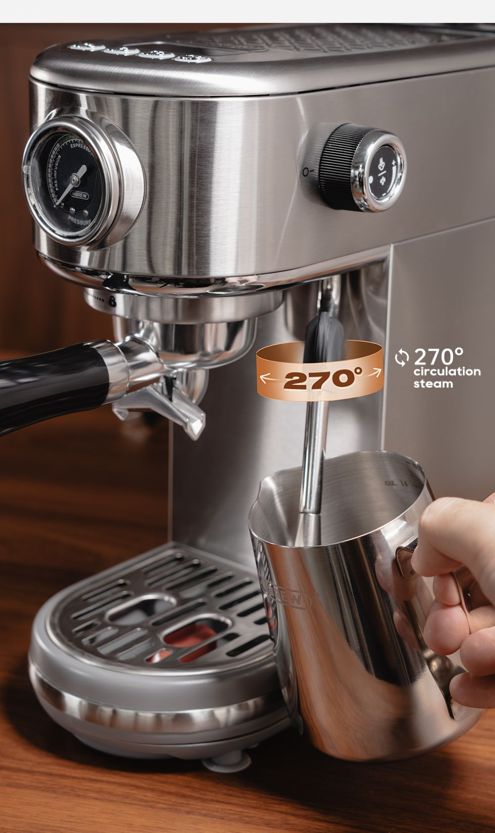 Una mano sostiene una jarra metálica bajo la varilla de vapor de una máquina de espresso plateada.