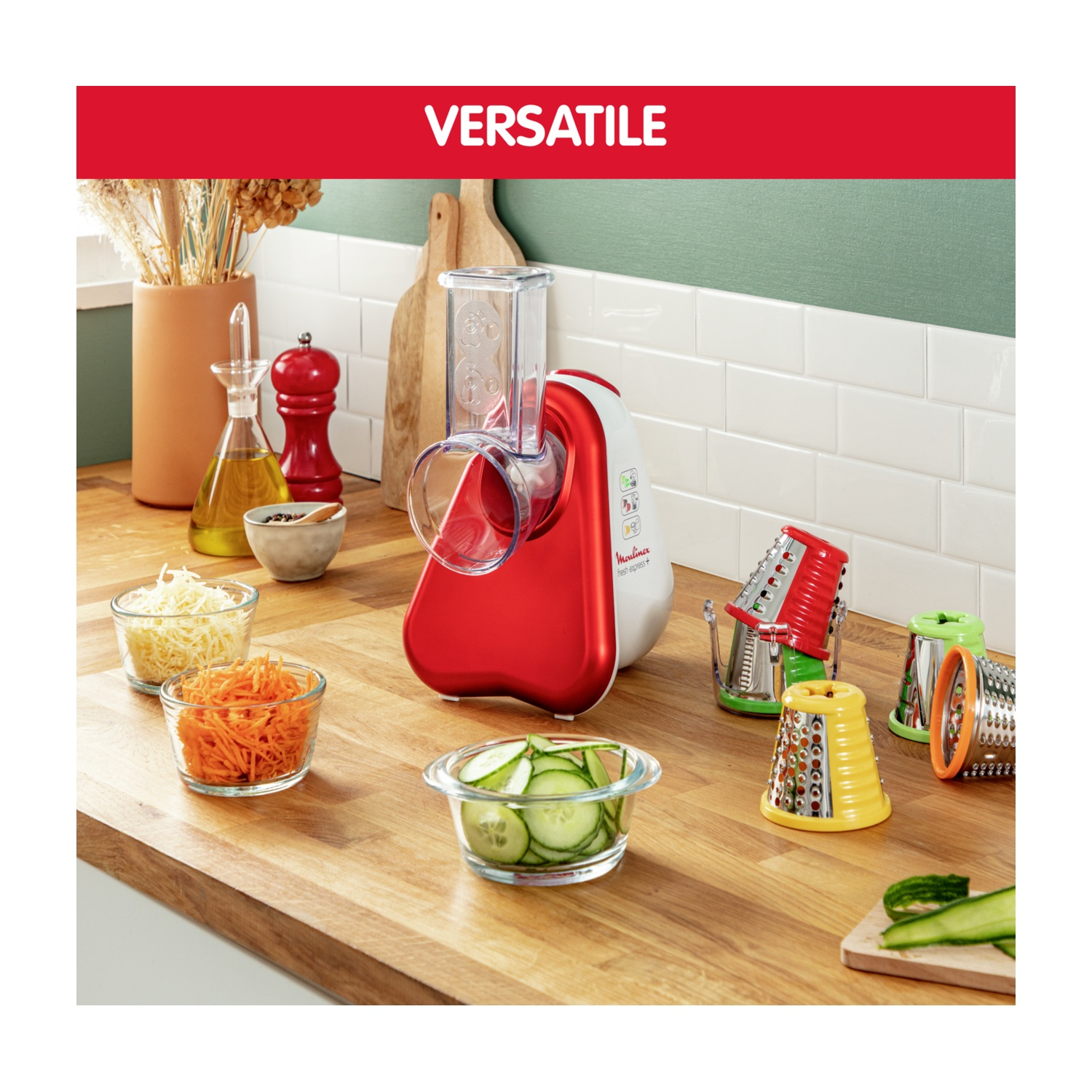Un robot da cucina rosso e bianco con accessori e ciotole di carote grattugiate, formaggio e cetriolo.