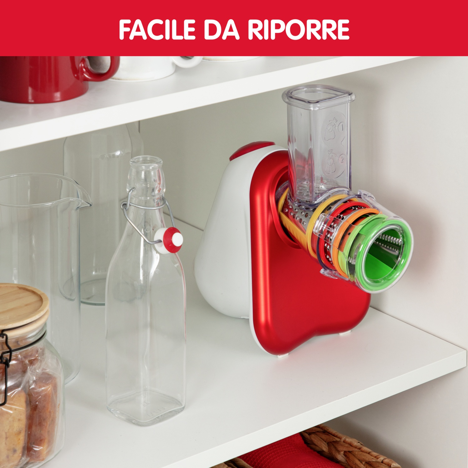 Un robot da cucina rosso e bianco con tamburi colorati è su uno scaffale.