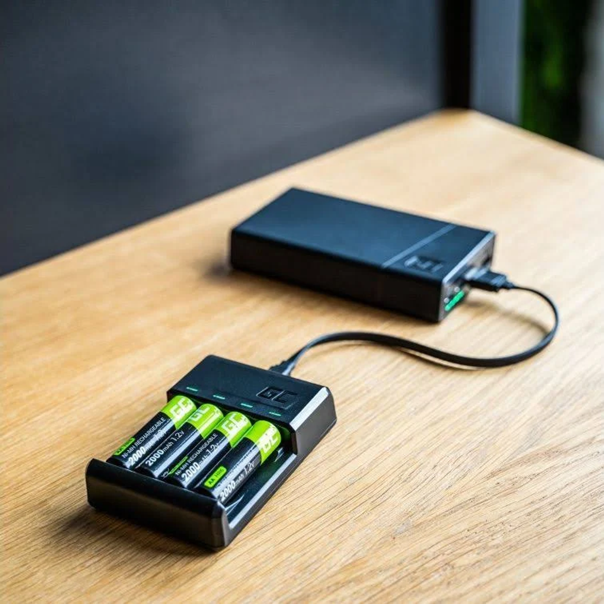 Un caricabatterie con quattro batterie AA è collegato a un power bank nero.