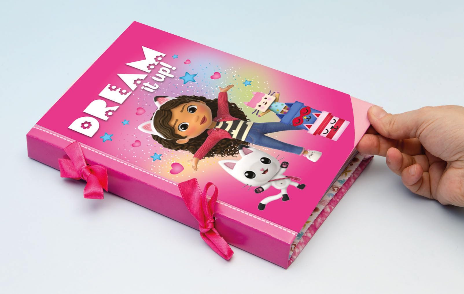 Una scatola rosa con Gabby e un gatto bianco sopra. Il testo dice DREAM it up!