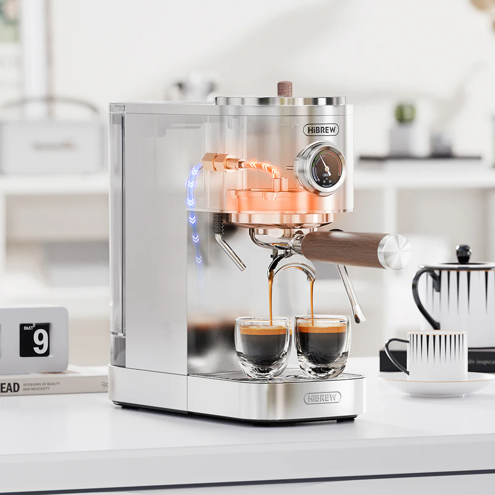 Una cafetera espresso plateada prepara café en dos vasos pequeños, tubos de cobre visibles.