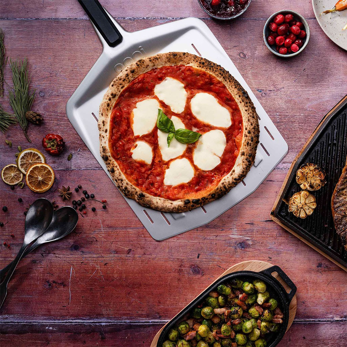 Una pizza margherita su una pala, con cavoletti di Bruxelles arrostiti e bistecca alla griglia.