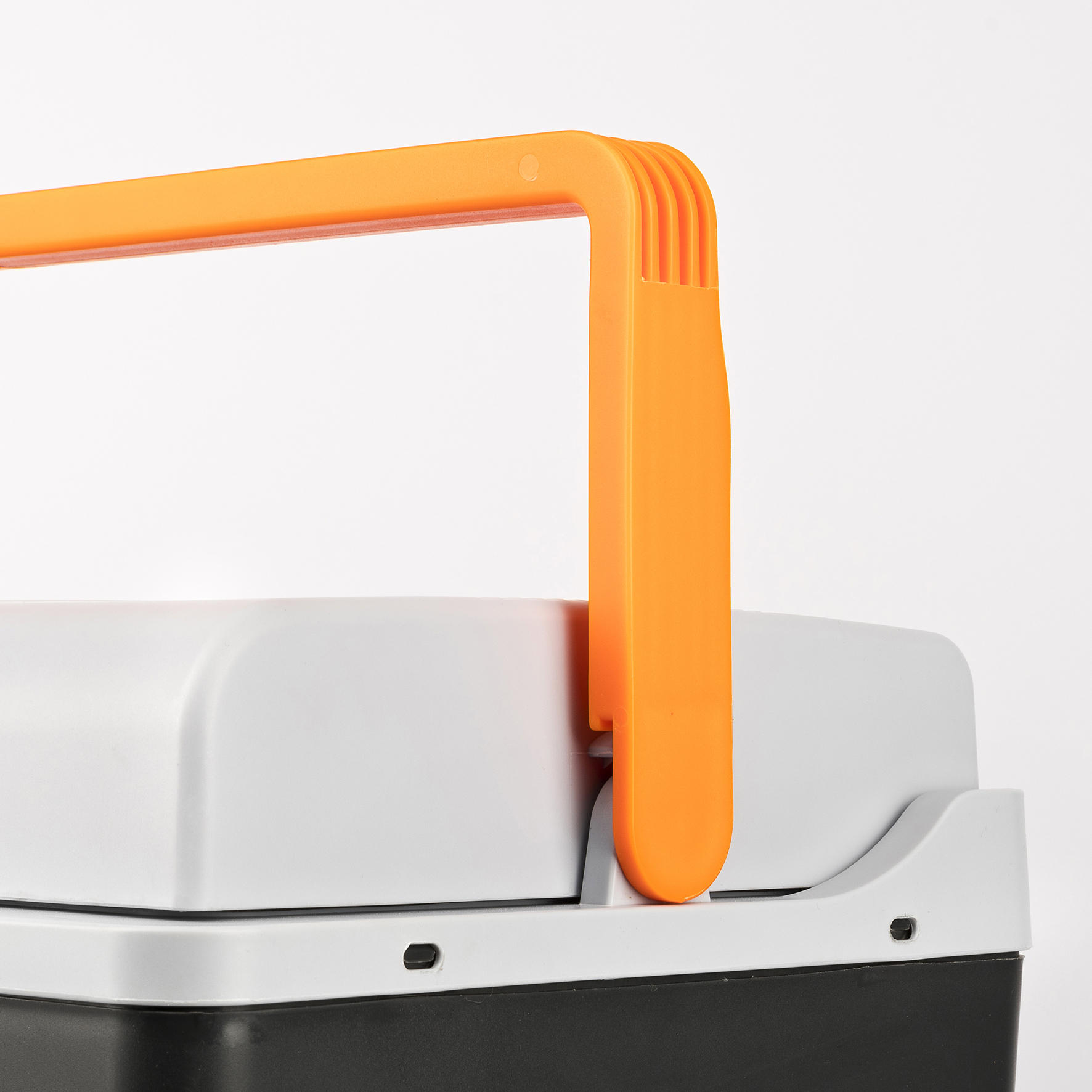 Close-up van de oranje handgreep en het grijze deksel van een draagbare koelbox.