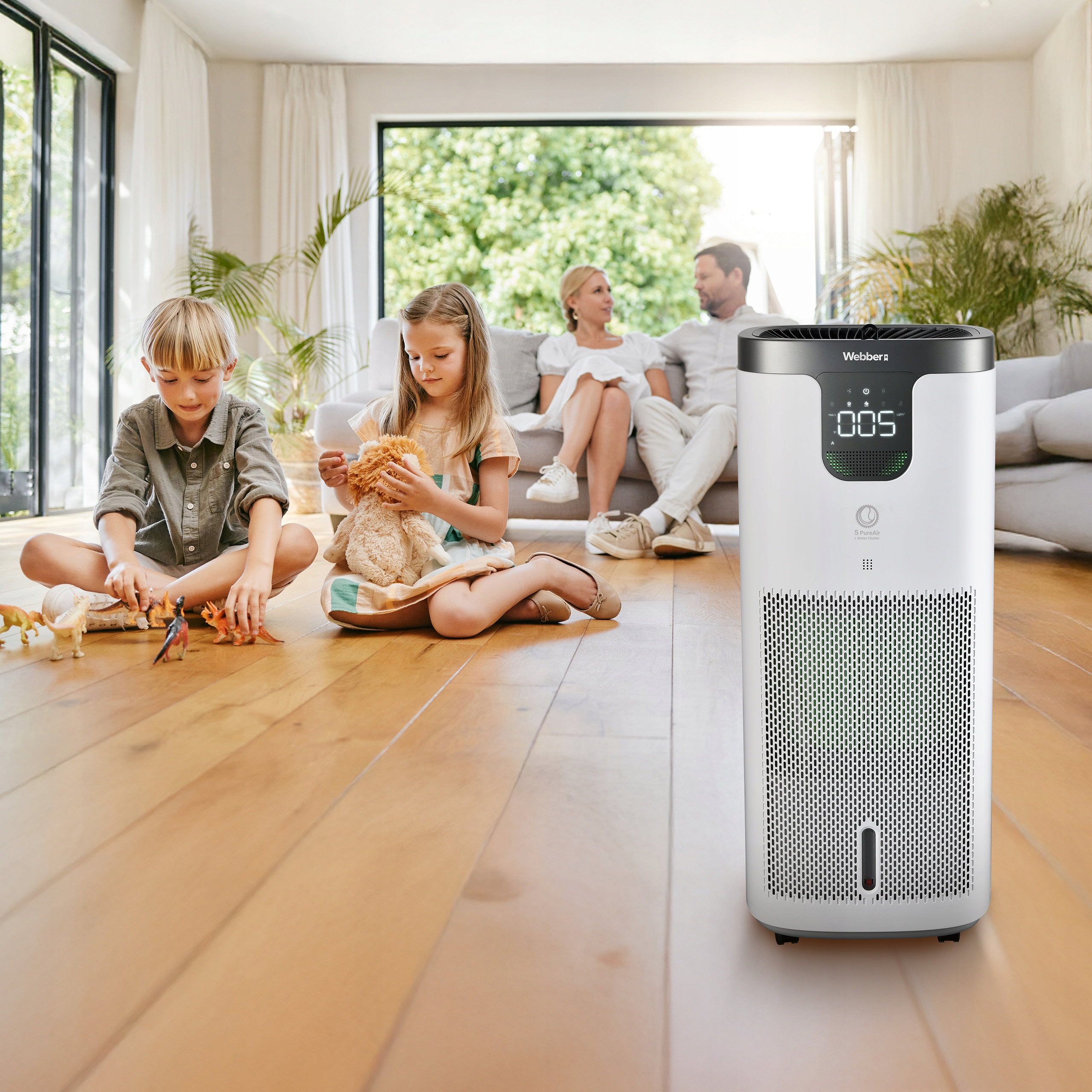 Rodzina w salonie, dzieci bawią się na podłodze, oczyszczacz powietrza na pierwszym planie.