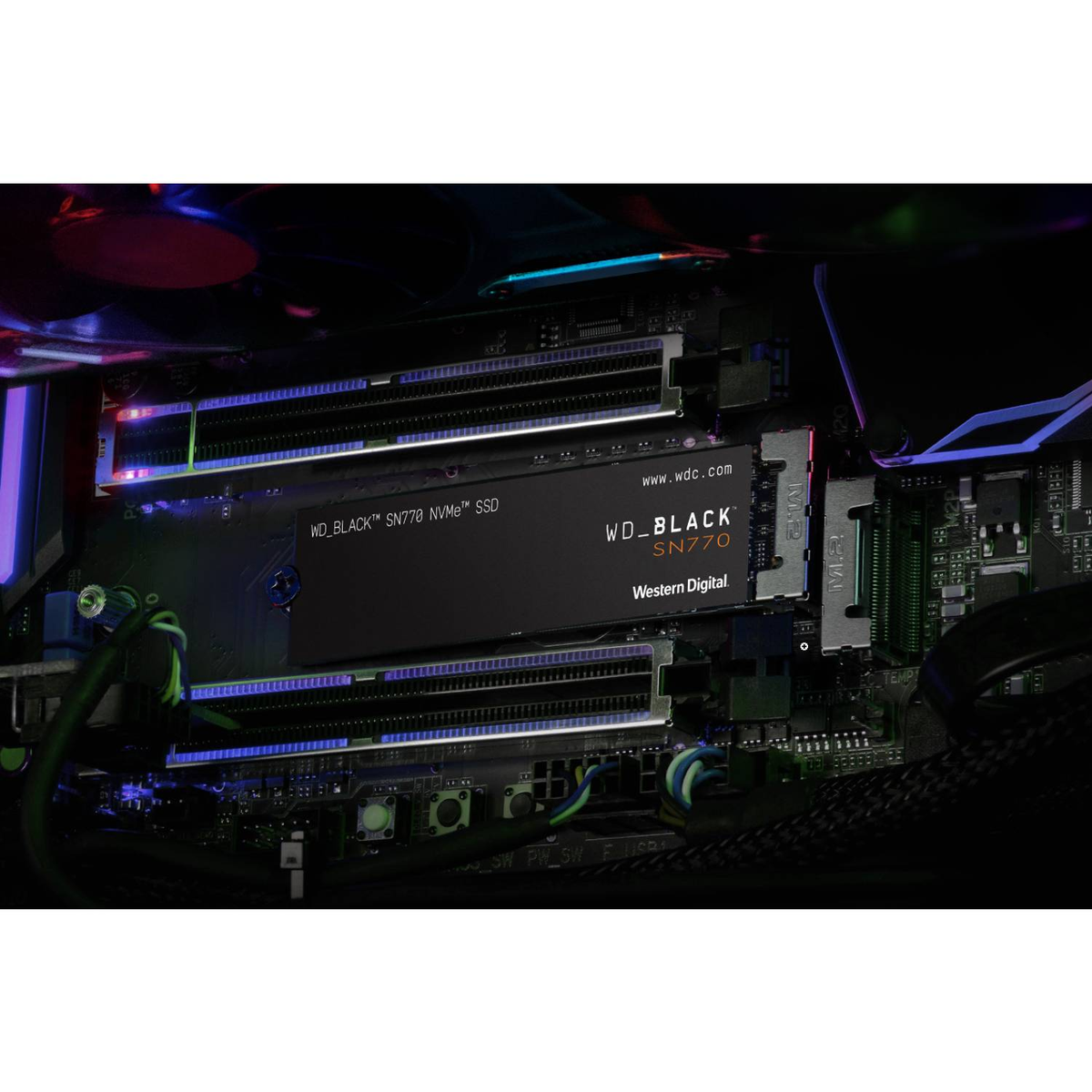 Un SSD NVMe WD_BLACK SN770 negro instalado en una placa base de computadora con iluminación RGB.