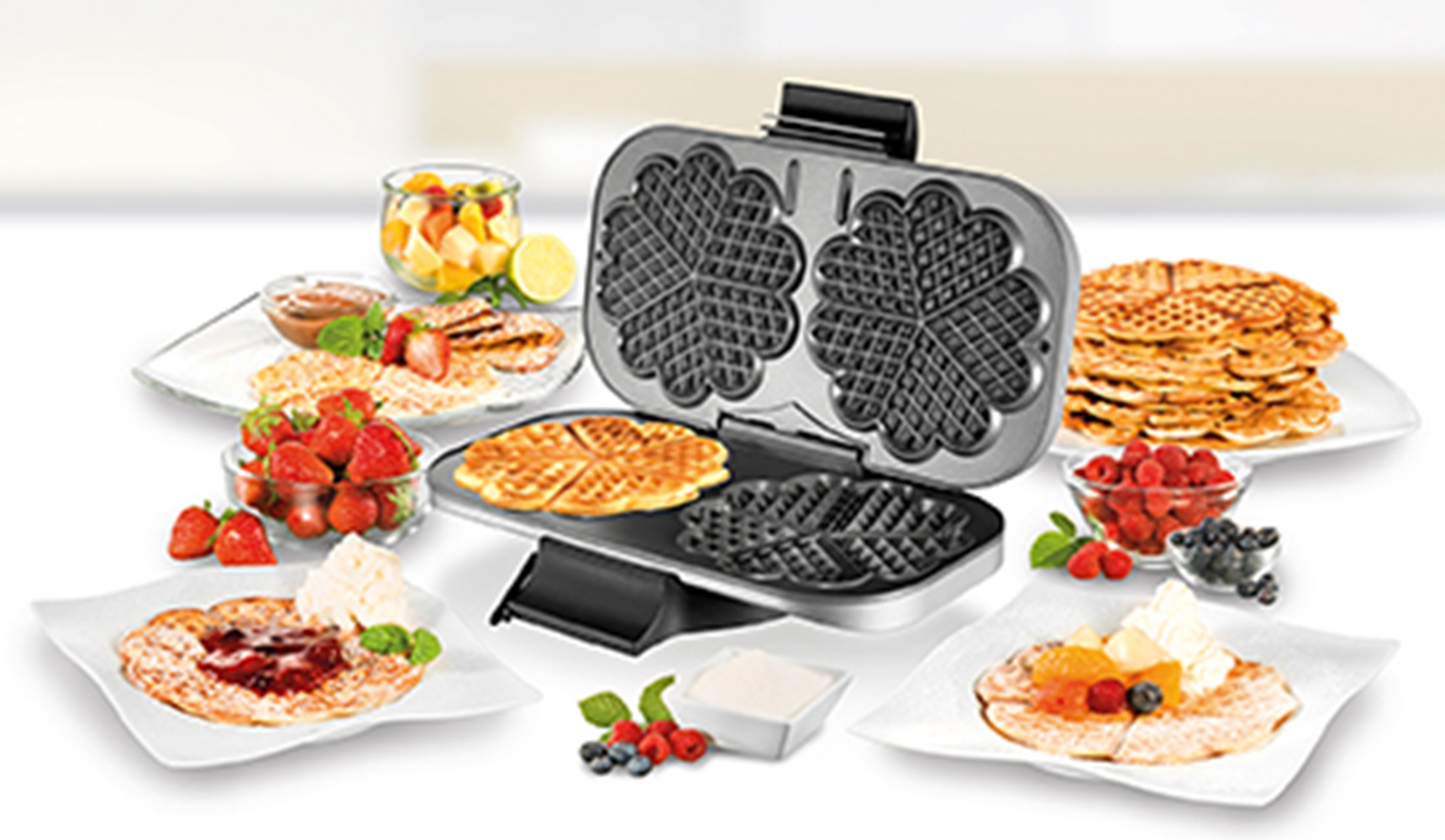 Gofrownica w kształcie serca z goframi, jagodami i sałatką owocową.