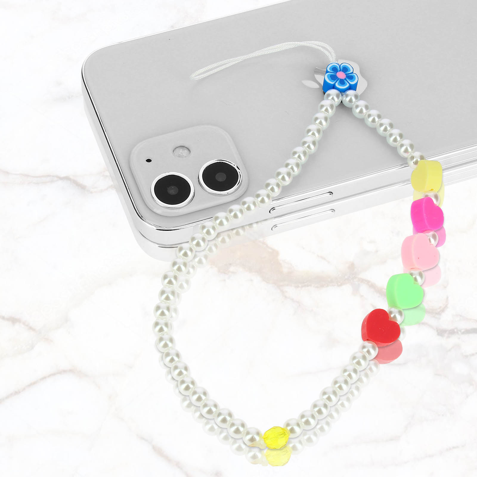 Uno smartphone bianco con un cinturino perla e cuore e un ciondolo a fiore blu.