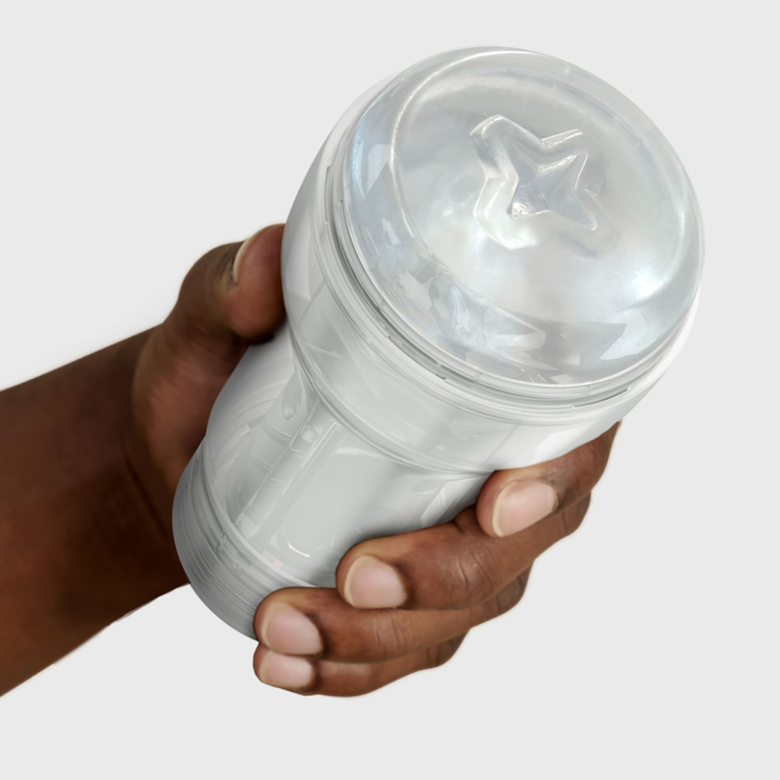 Una mano oscura sostiene una taza blanca y transparente con un patrón de estrellas en su interior.