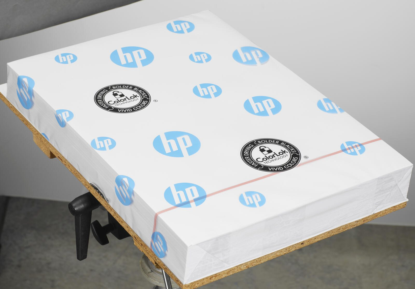 Una pila di carta HP con tecnologia ColorLok è fissata su una tavola di legno.
