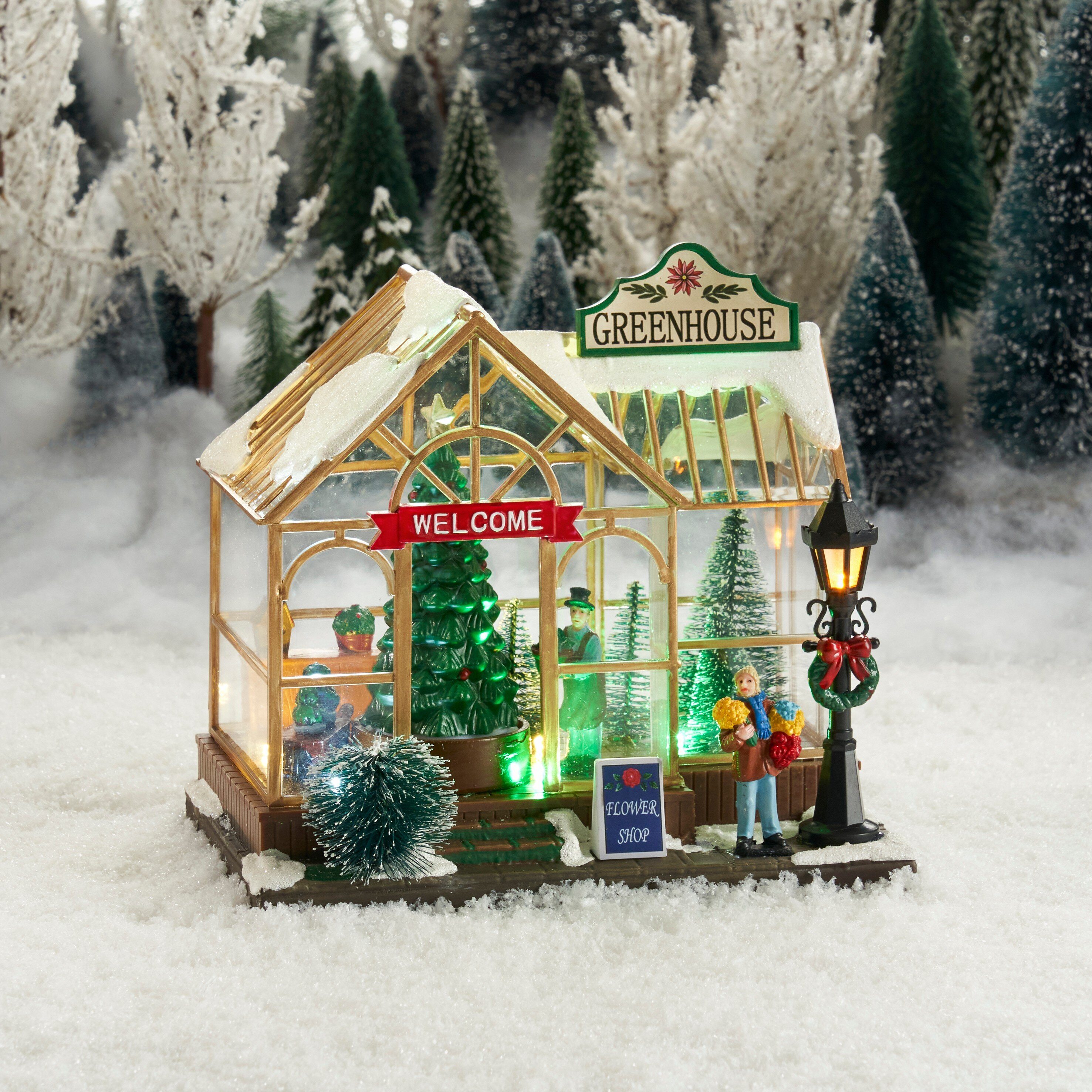 Een winterse kasdiorama met verlichte bomen en een figuur.