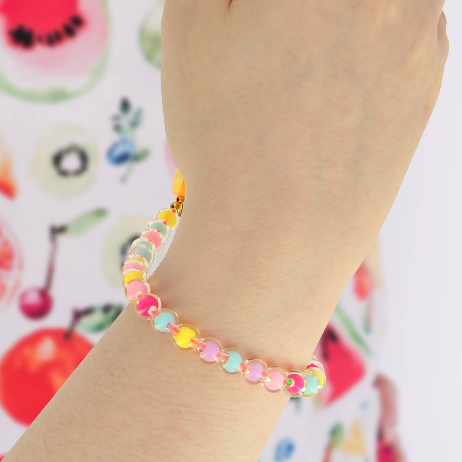 Bracciale con perline colorate e ciondolo a fetta d'arancia su un braccio.