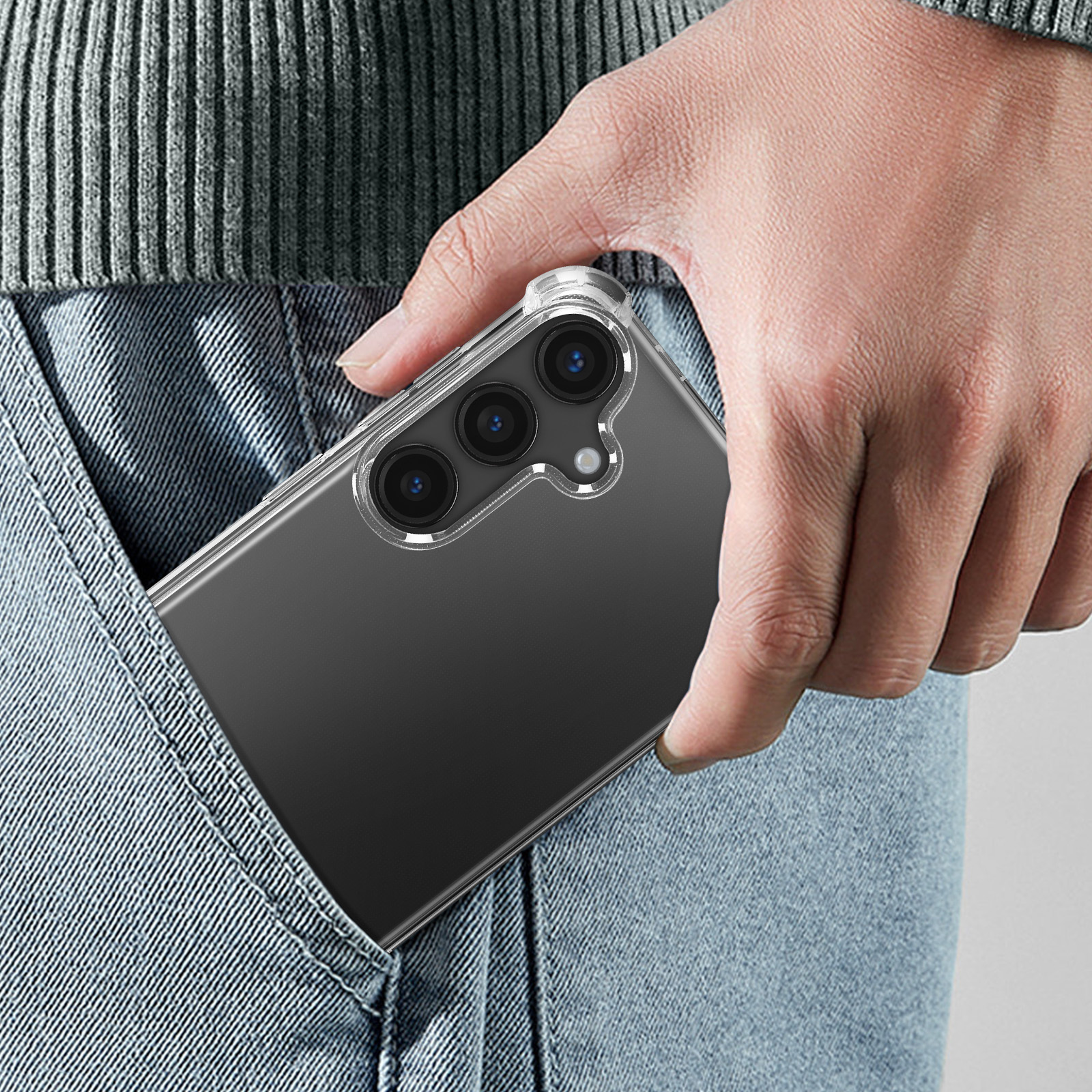 Una mano inserisce una custodia trasparente per telefono con tre fotocamere in una tasca di jeans.