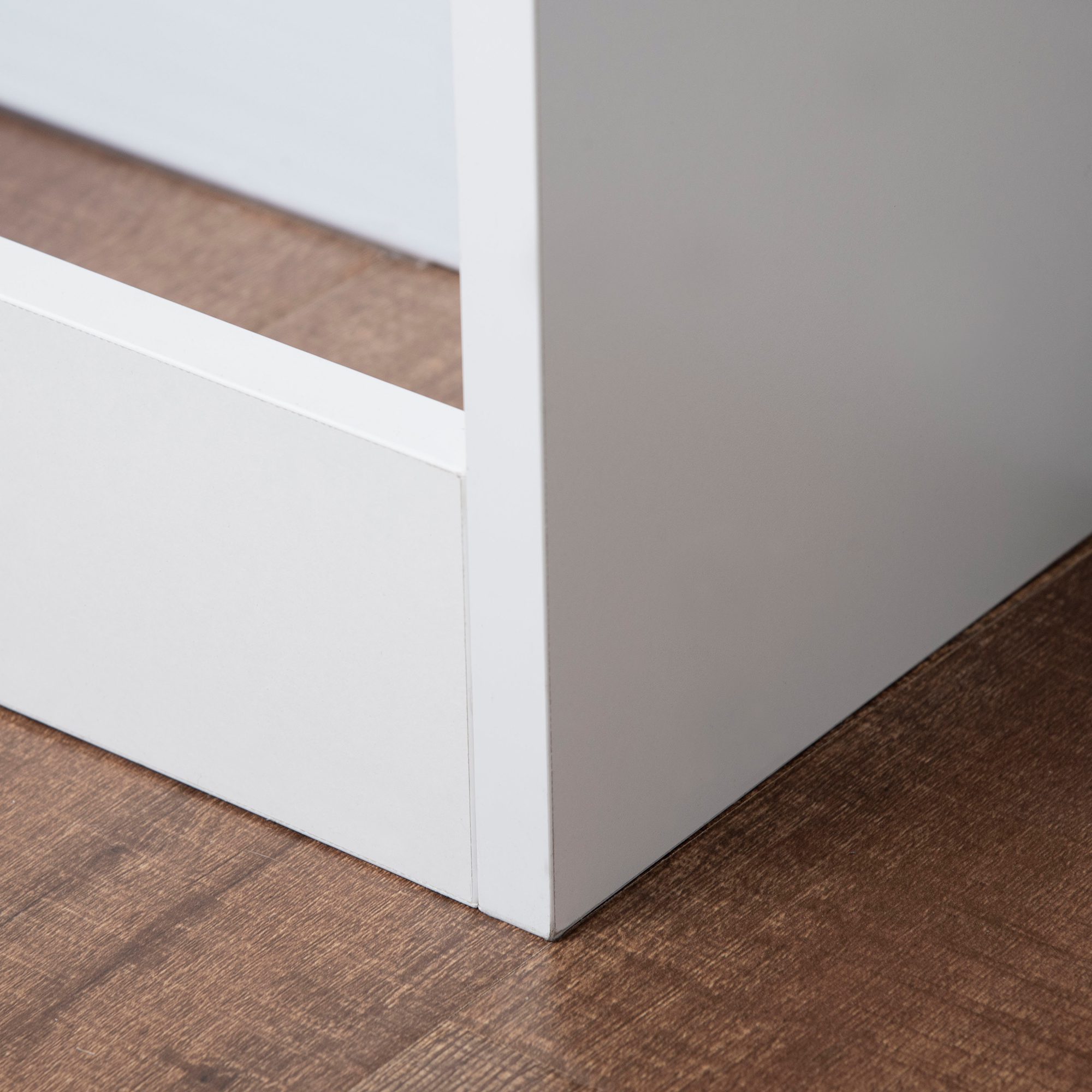 Primo piano di un angolo di mobile bianco su pavimento in legno.