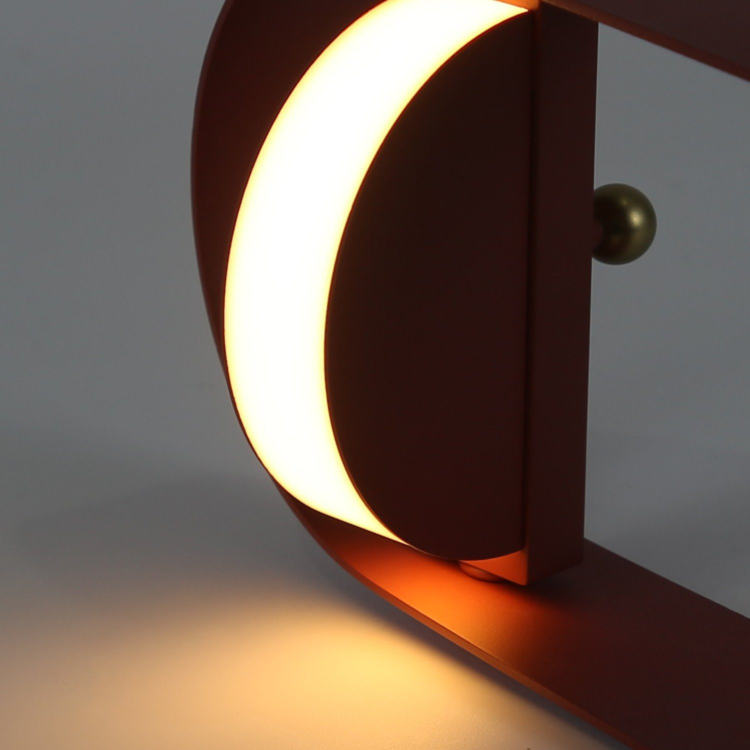 Una luce rossa decorativa con un arco luminoso e una manopola dorata.