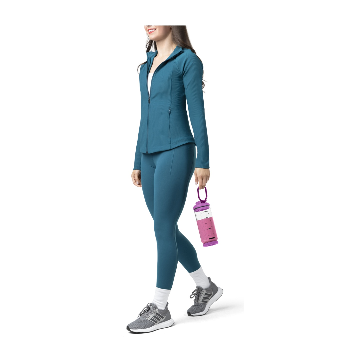 Donna in abbigliamento sportivo blu cammina tenendo una borraccia rosa.