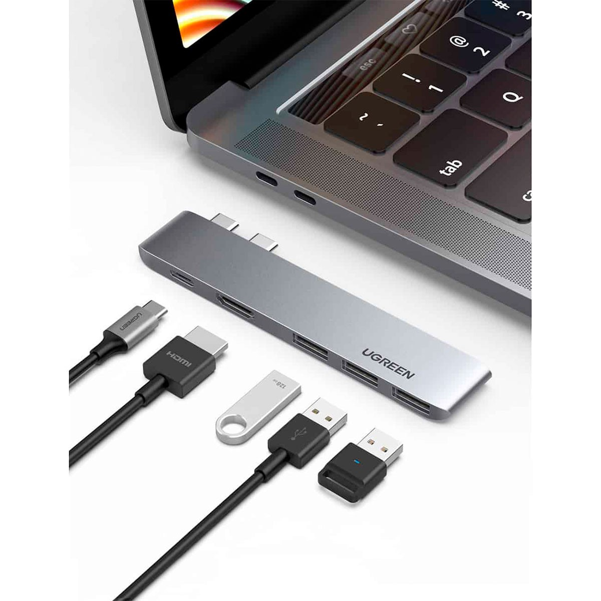 Srebrny hub USB-C podłączony do laptopa, z kablami HDMI i USB.