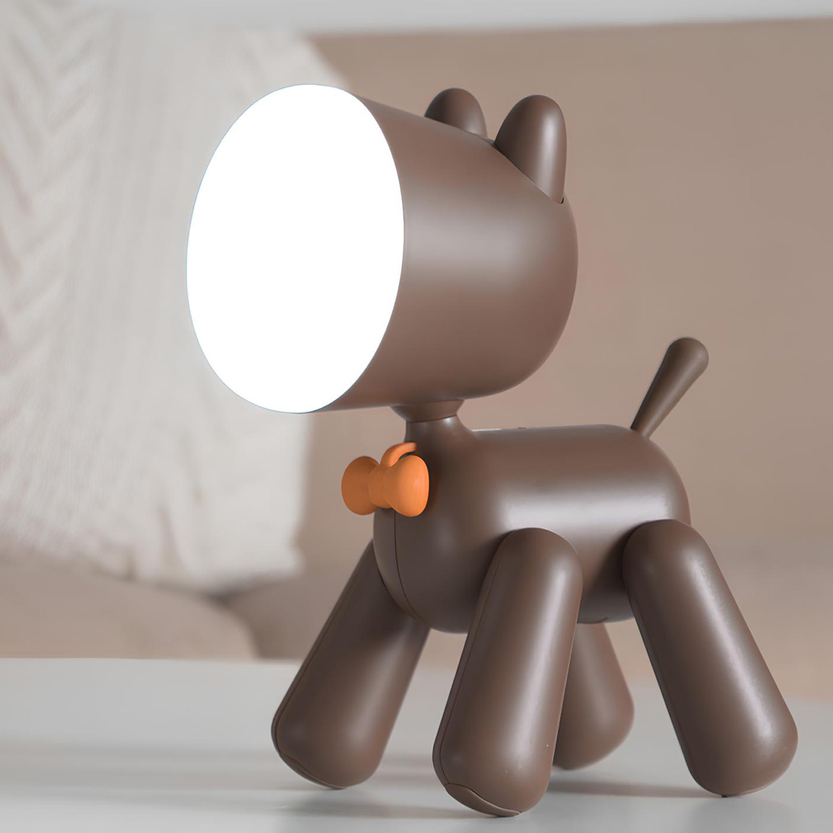 Ein brauner Hundelampen-Nachttisch mit orangefarbener Schleife leuchtet hell.